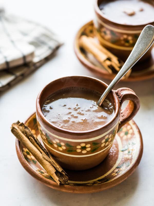 A mug of Mexican champurrado with a cinnamon stick.