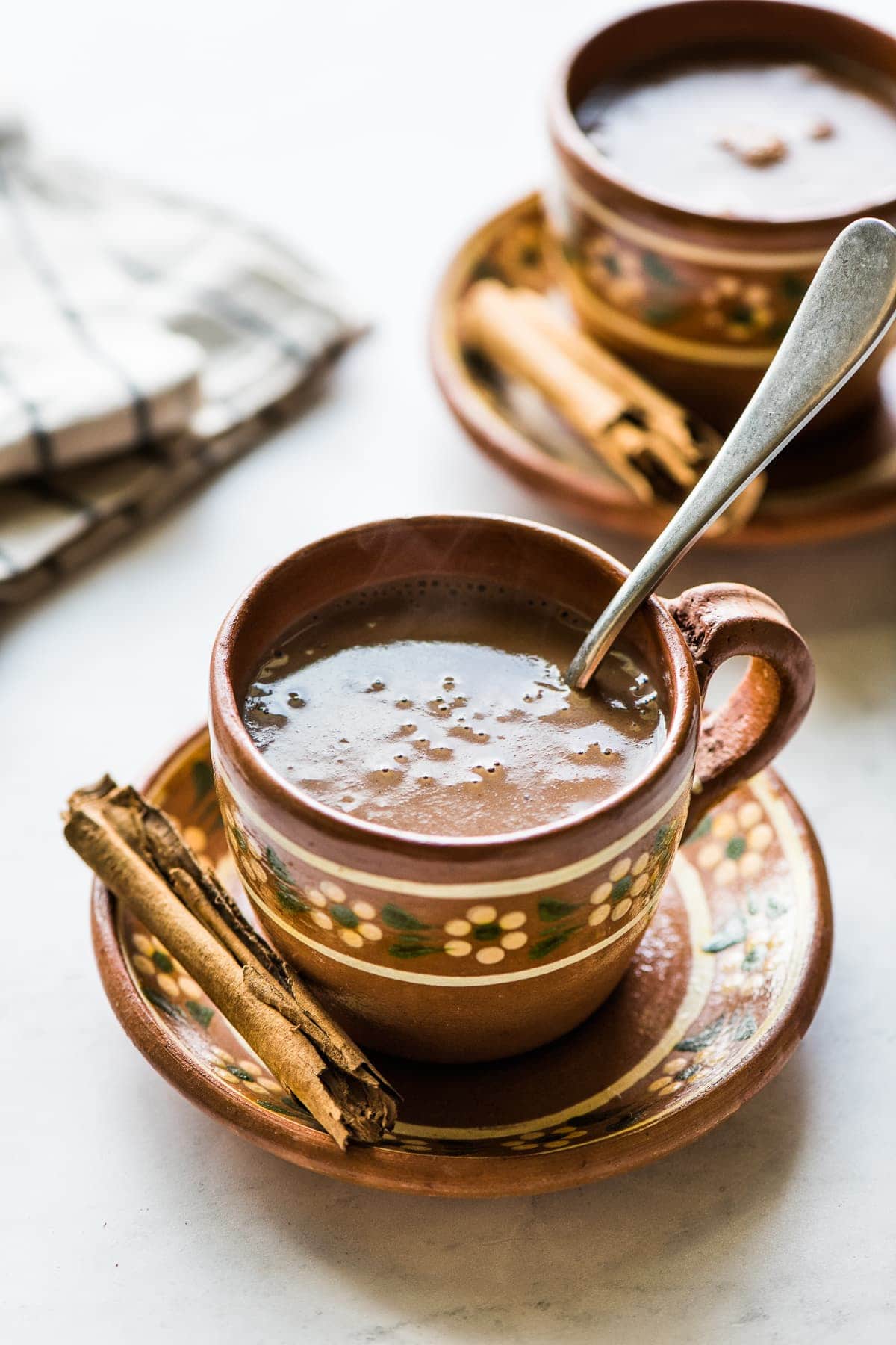 A mug of Mexican champurrado with a cinnamon stick.