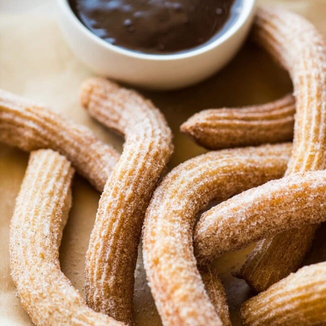 Churros coated with cinnamon sugar on a serving platter.