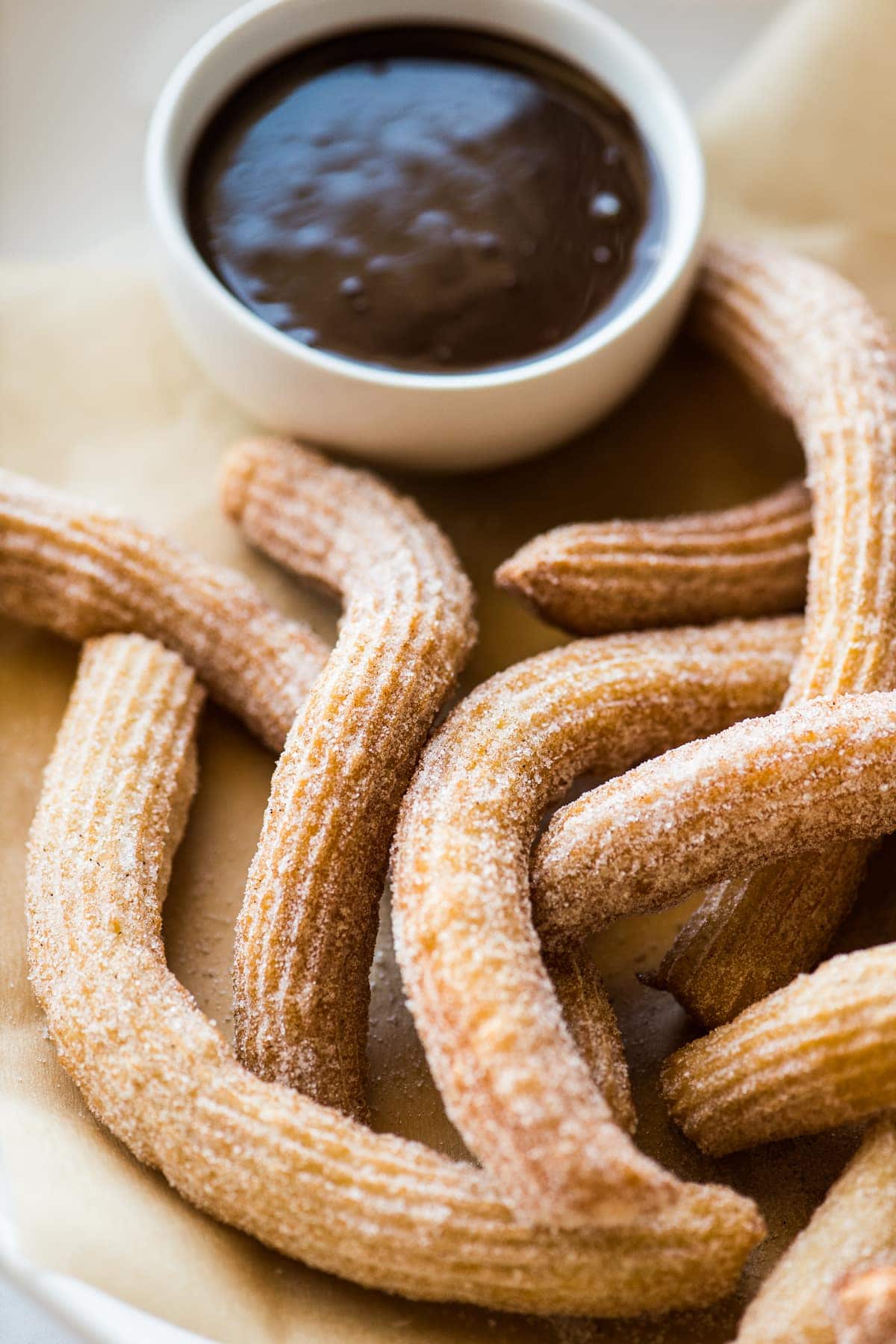 Churros coated with cinnamon sugar on a serving platter.