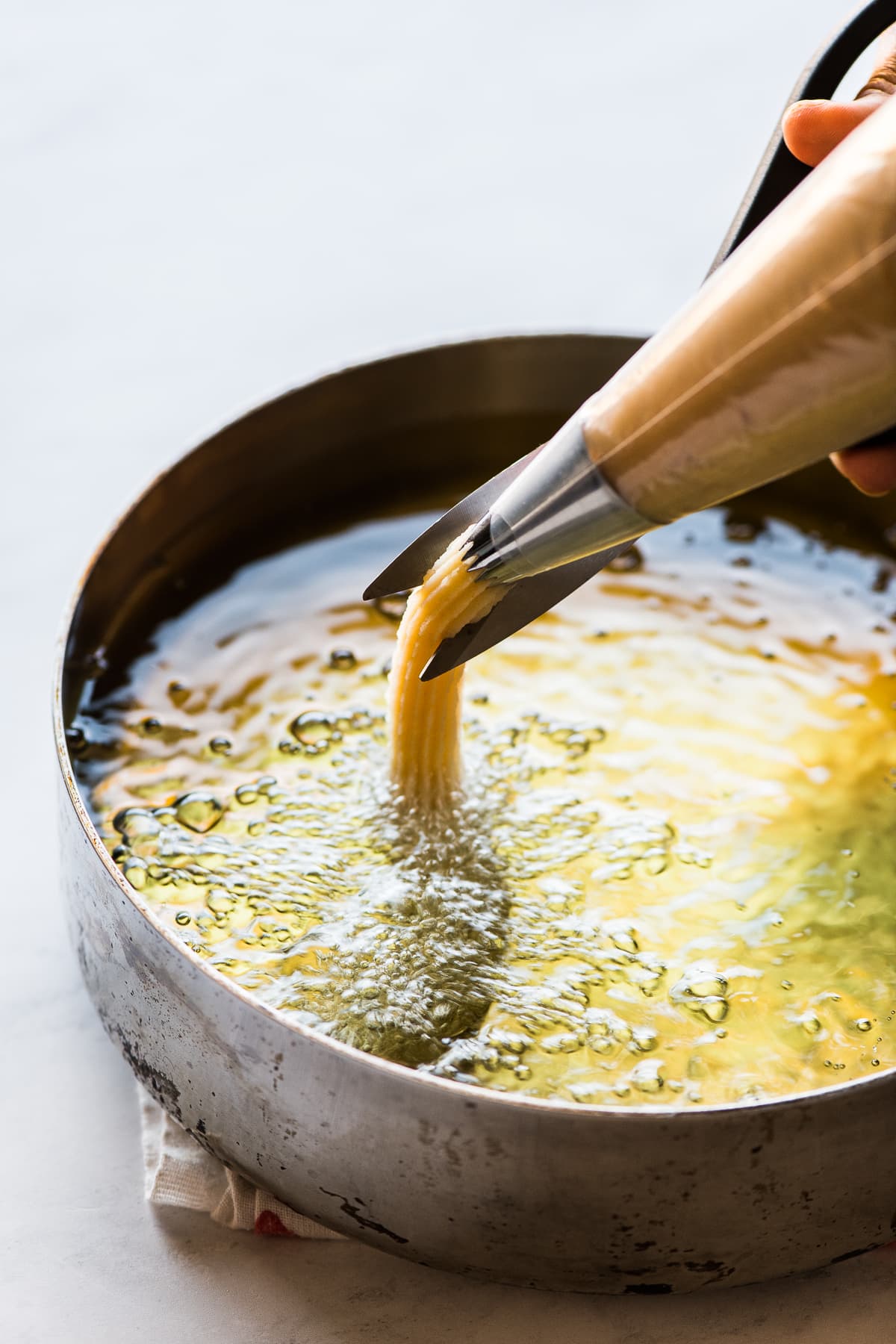 Churros being piped in hot oil for frying.