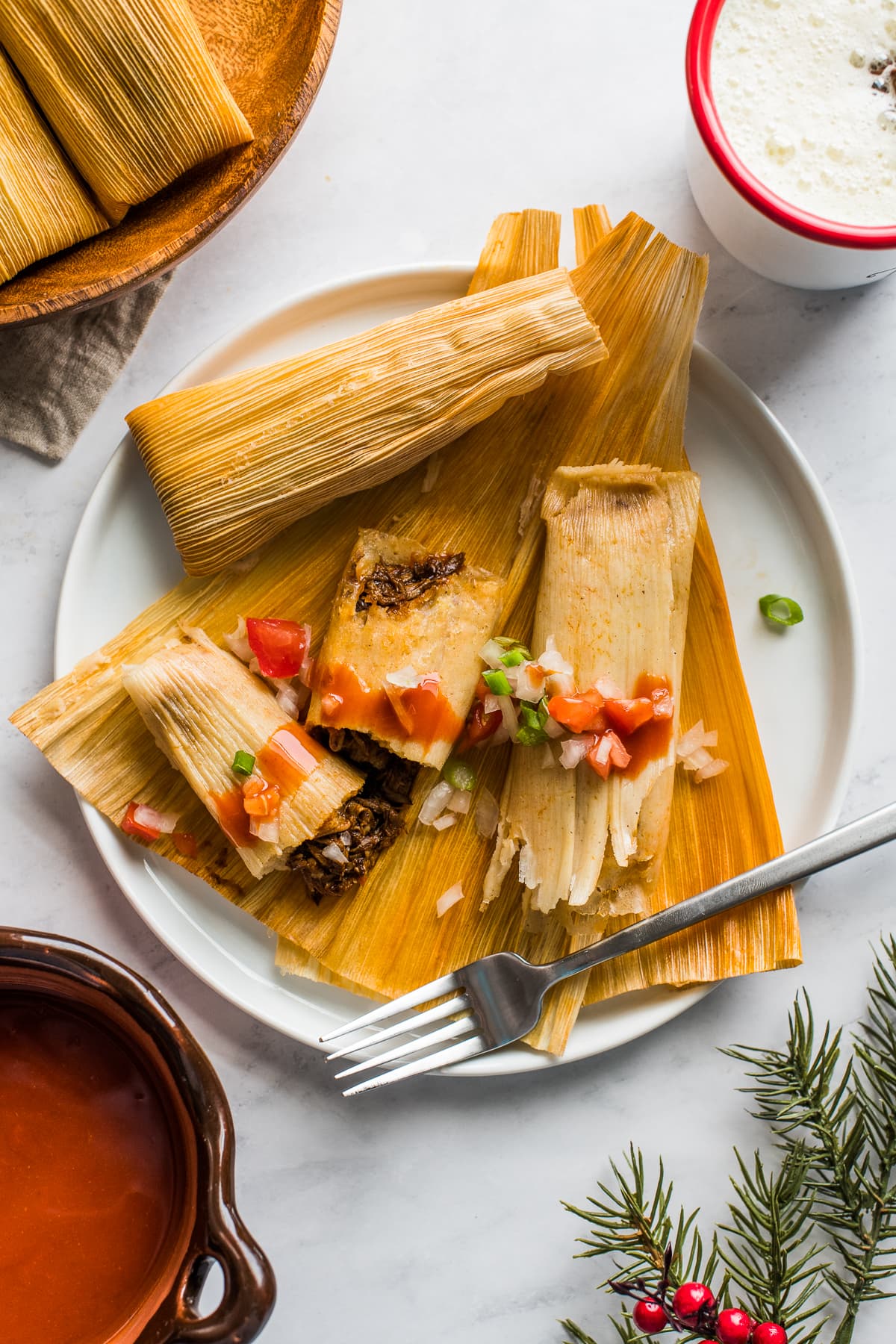 Instant Pot Tamales on a plate topped with tomatoes and onions.