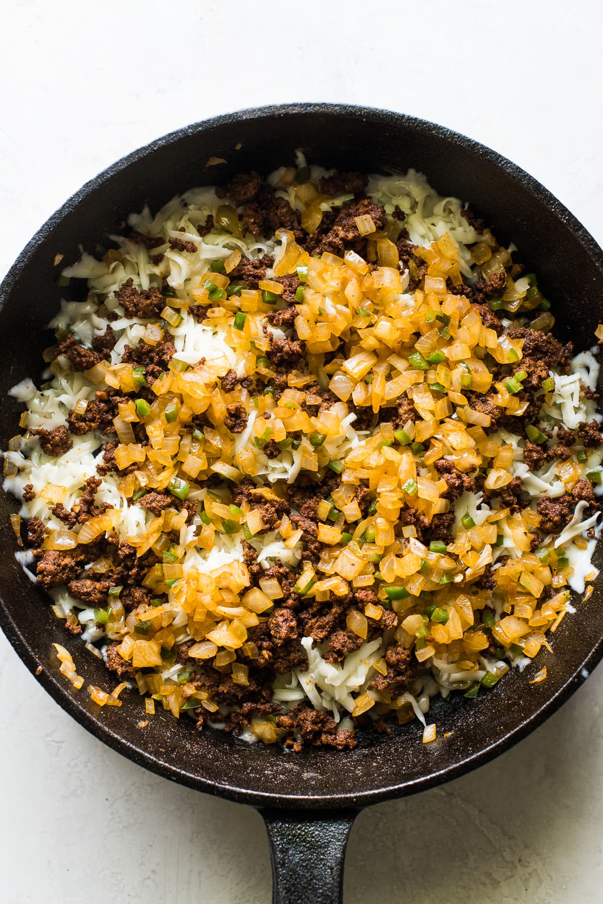 Sauteed onions, peppers, and chorizo in a skillet for queso fundido.