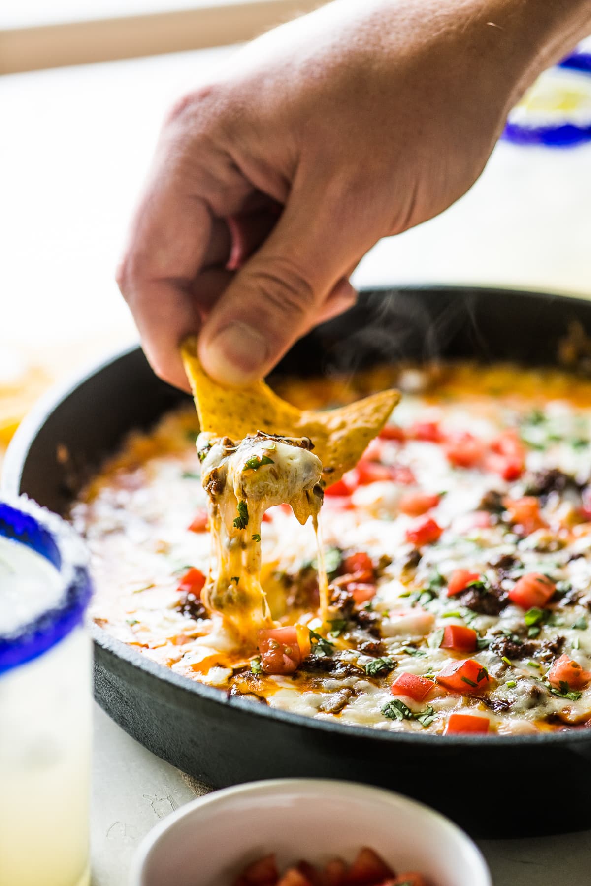 A tortilla chip being dipped in queso fundido.