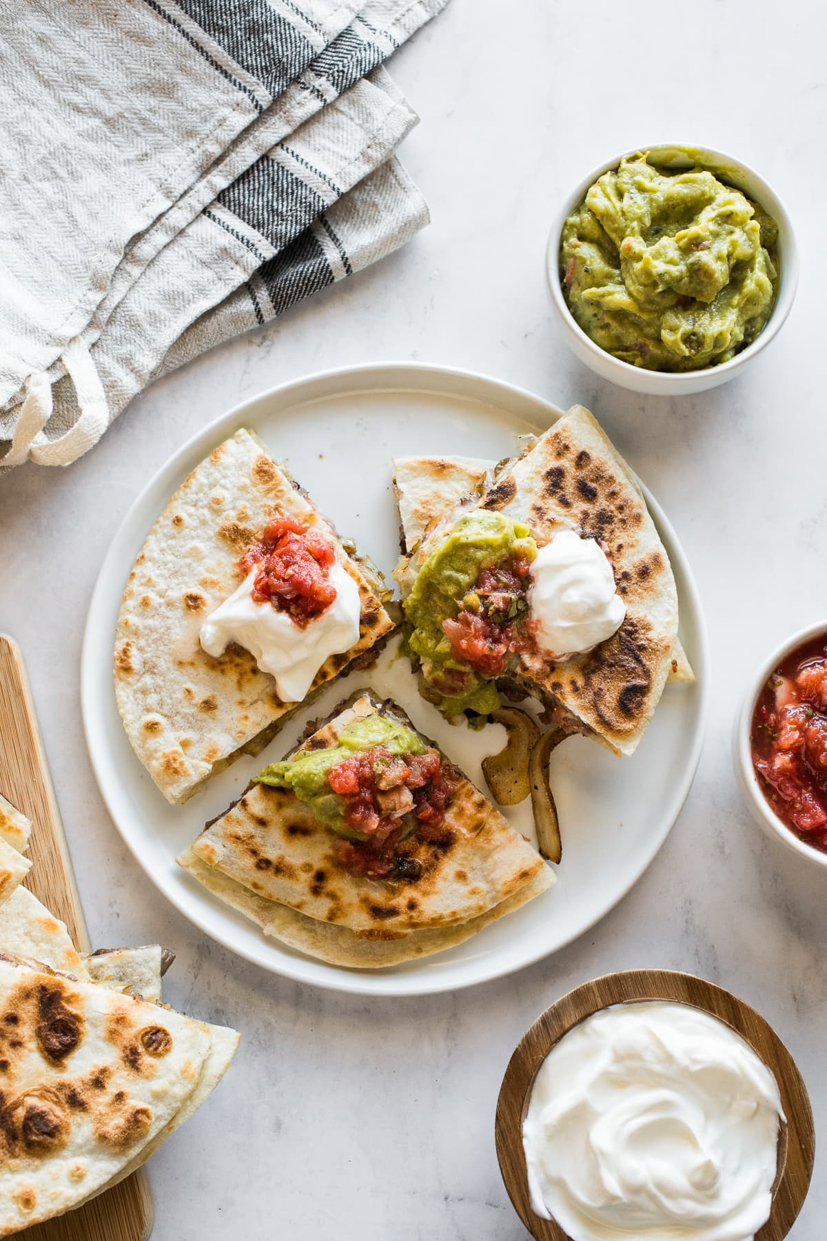A steak quesadilla topped with sour cream, salsa, and guacamole.
