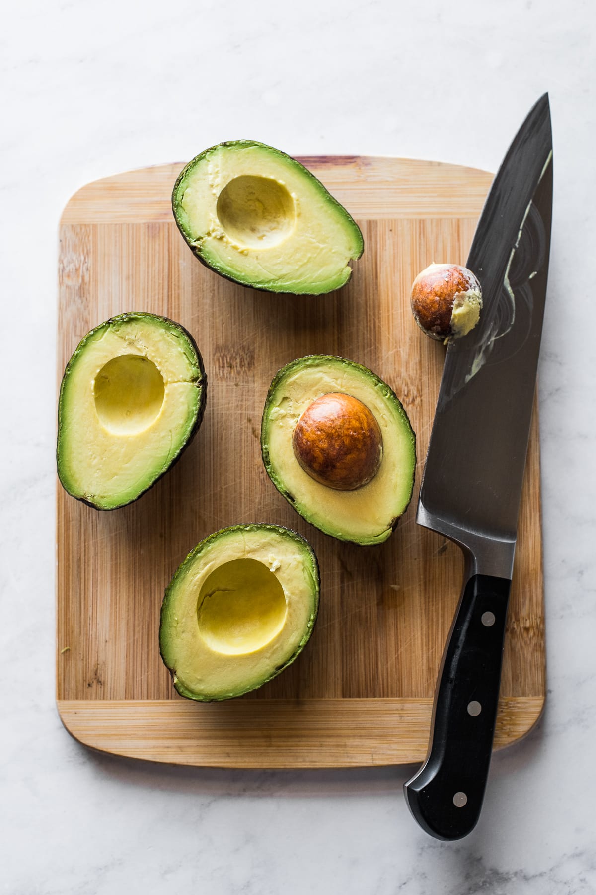 Avocado halves on a cutting board.