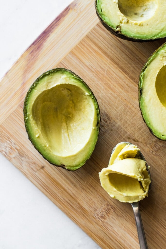 An avocado with some of the fruit scooped out of the middle to create a well.