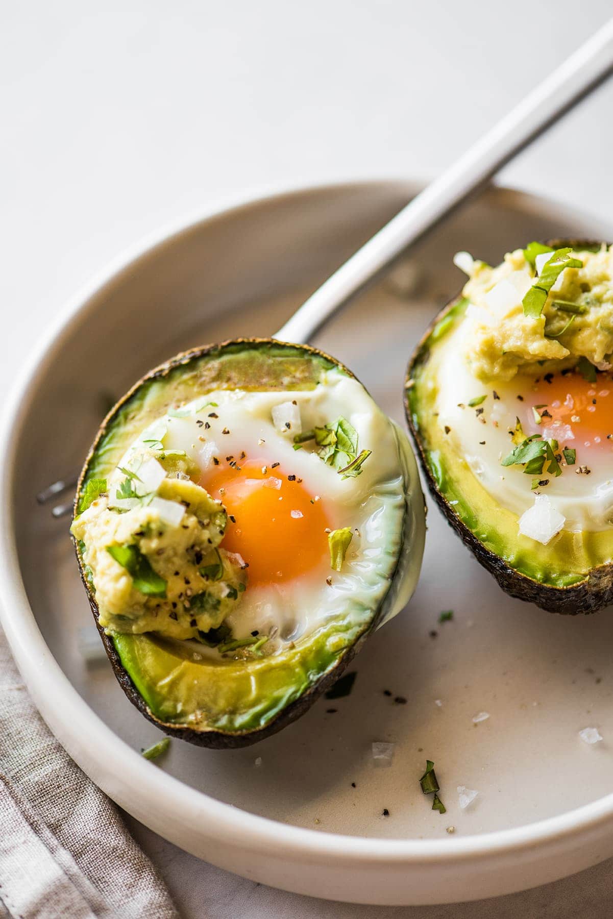 Avocado Egg Bake in a bowl seasoned with salt and pepper.