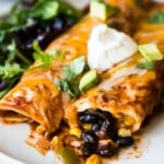 Black bean enchiladas topped with sour cream and cilantro.