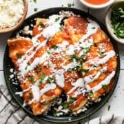 Entomatadas on a plate garnished with Mexican crema, cotija cheese, and cilantro.