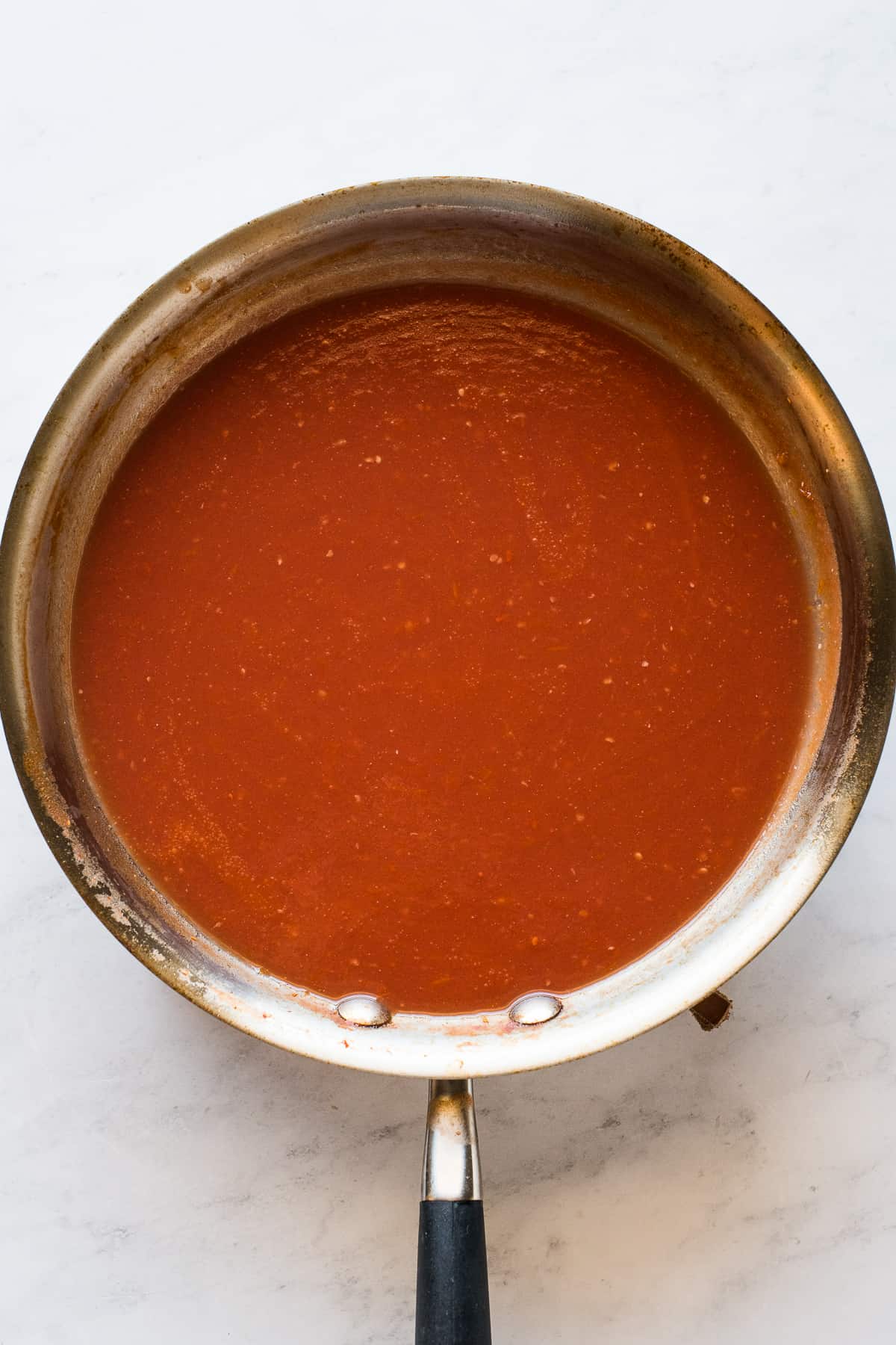 The tomato-based sauce for entomatadas in a skillet.