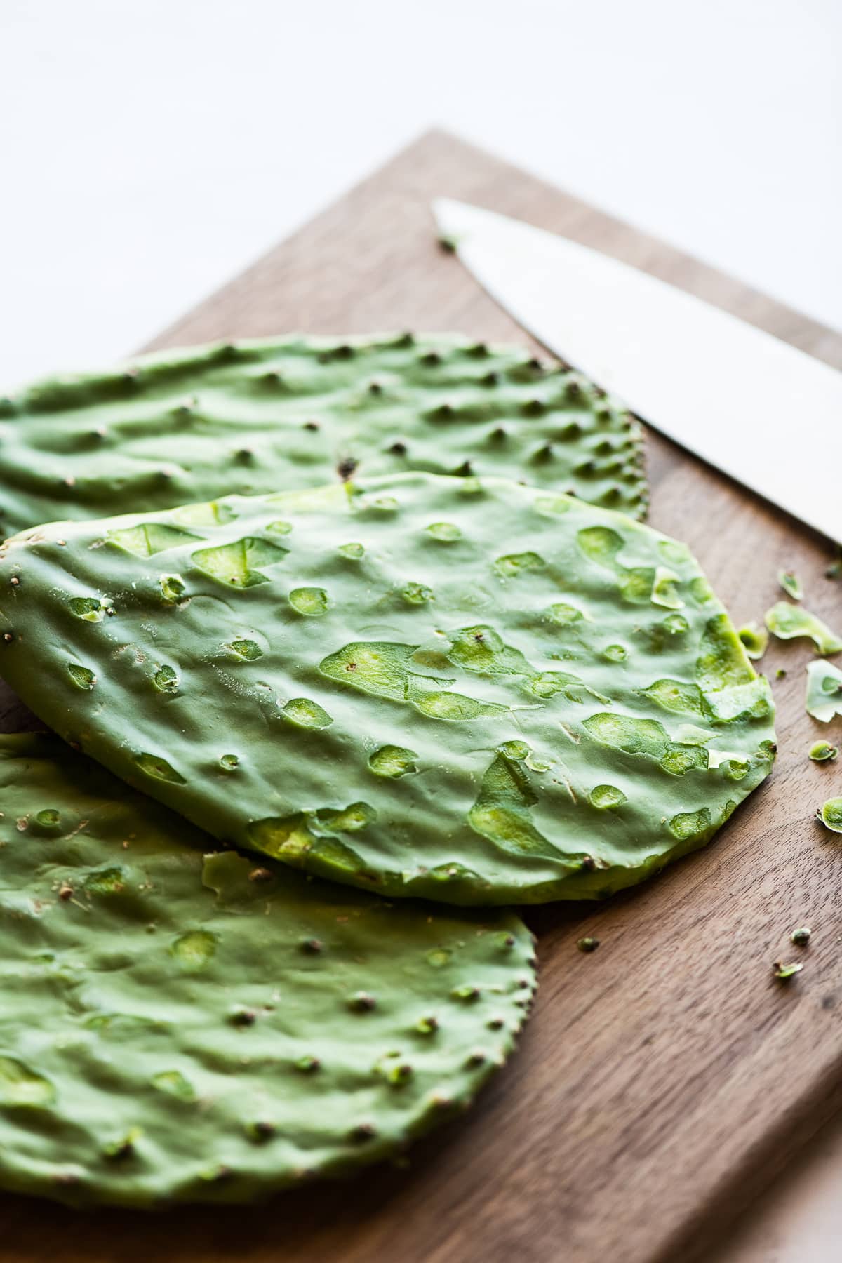 Nopales on a cutting board with spines and thorns sliced off.