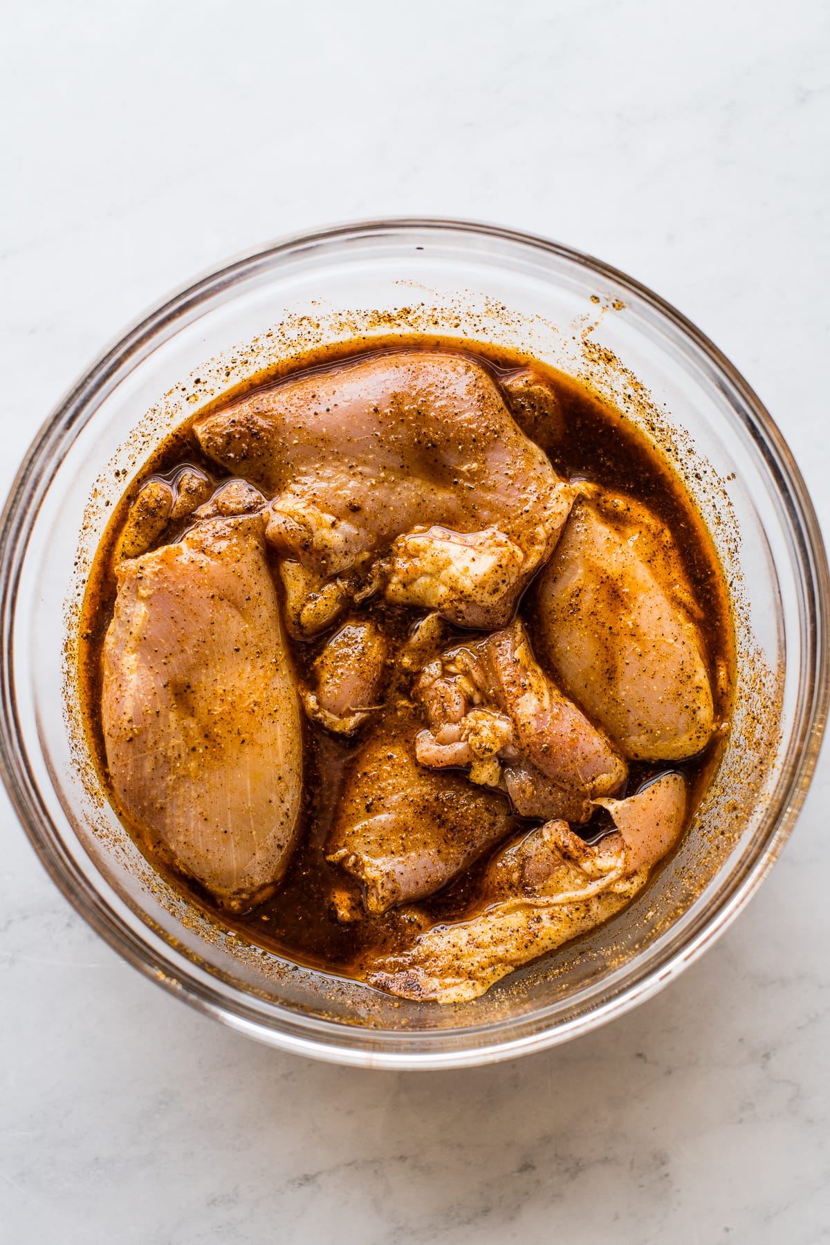 Chicken thighs marinating in a bowl.