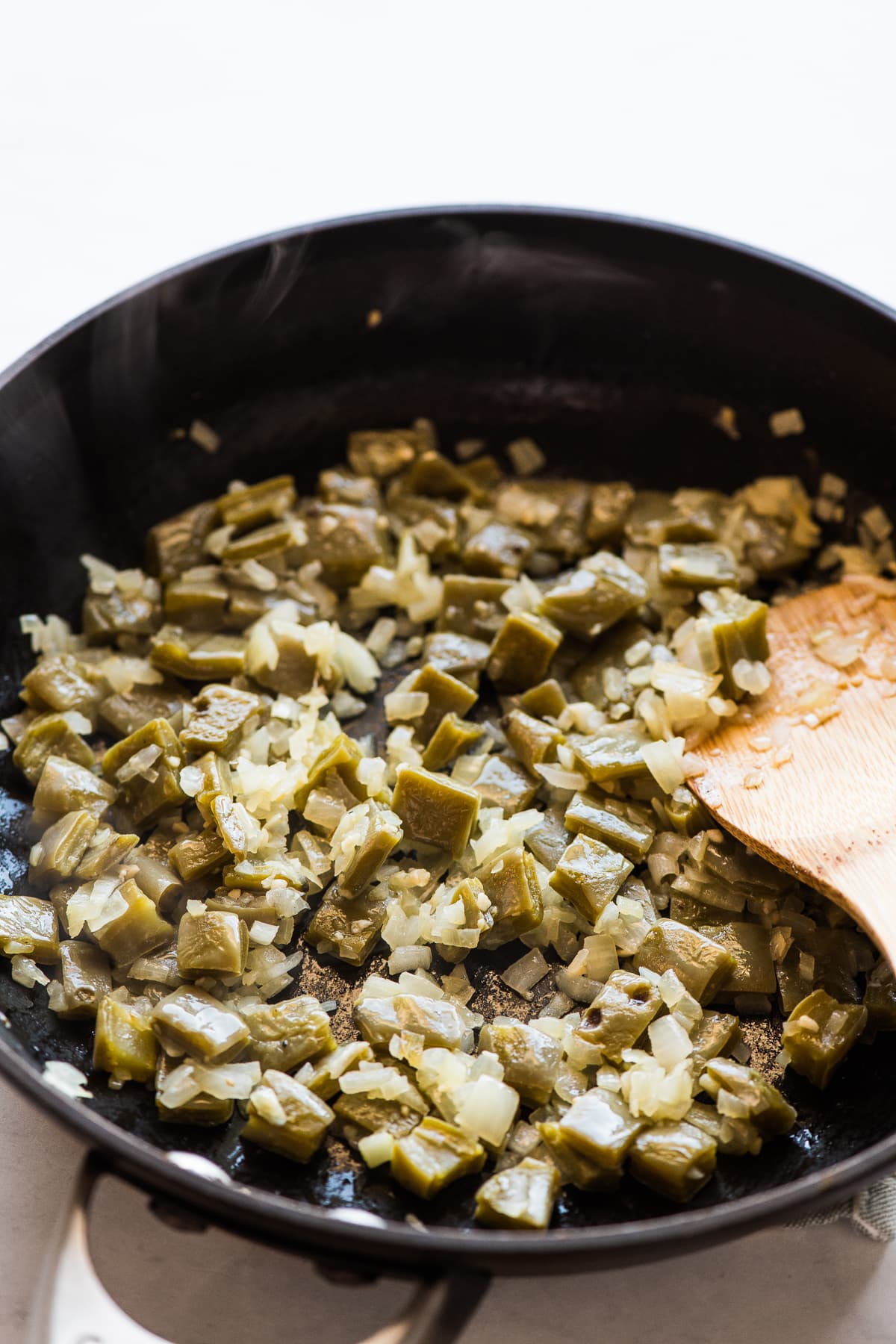 Nopales, onions, and garlic cooking in a skillet