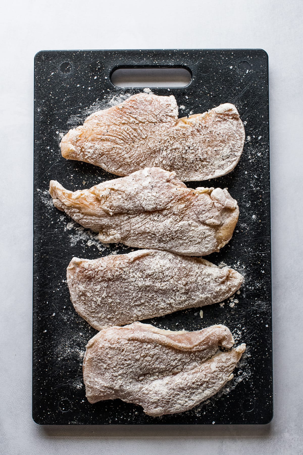 Sliced chicken breasts coated in flour for Pollo en Chipotle.