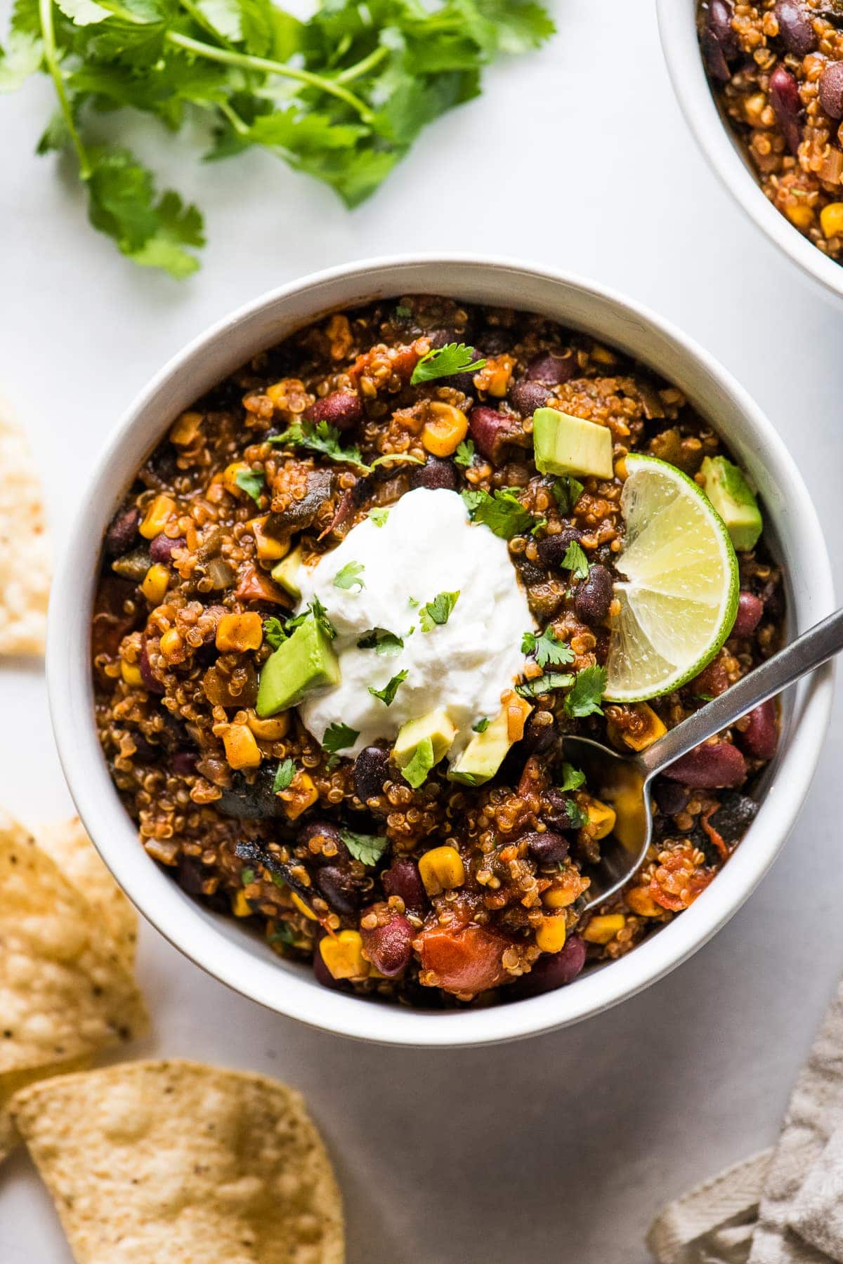 Quinoa black bean chili in a bowl topped with cilantro, avocados, and sour cream.