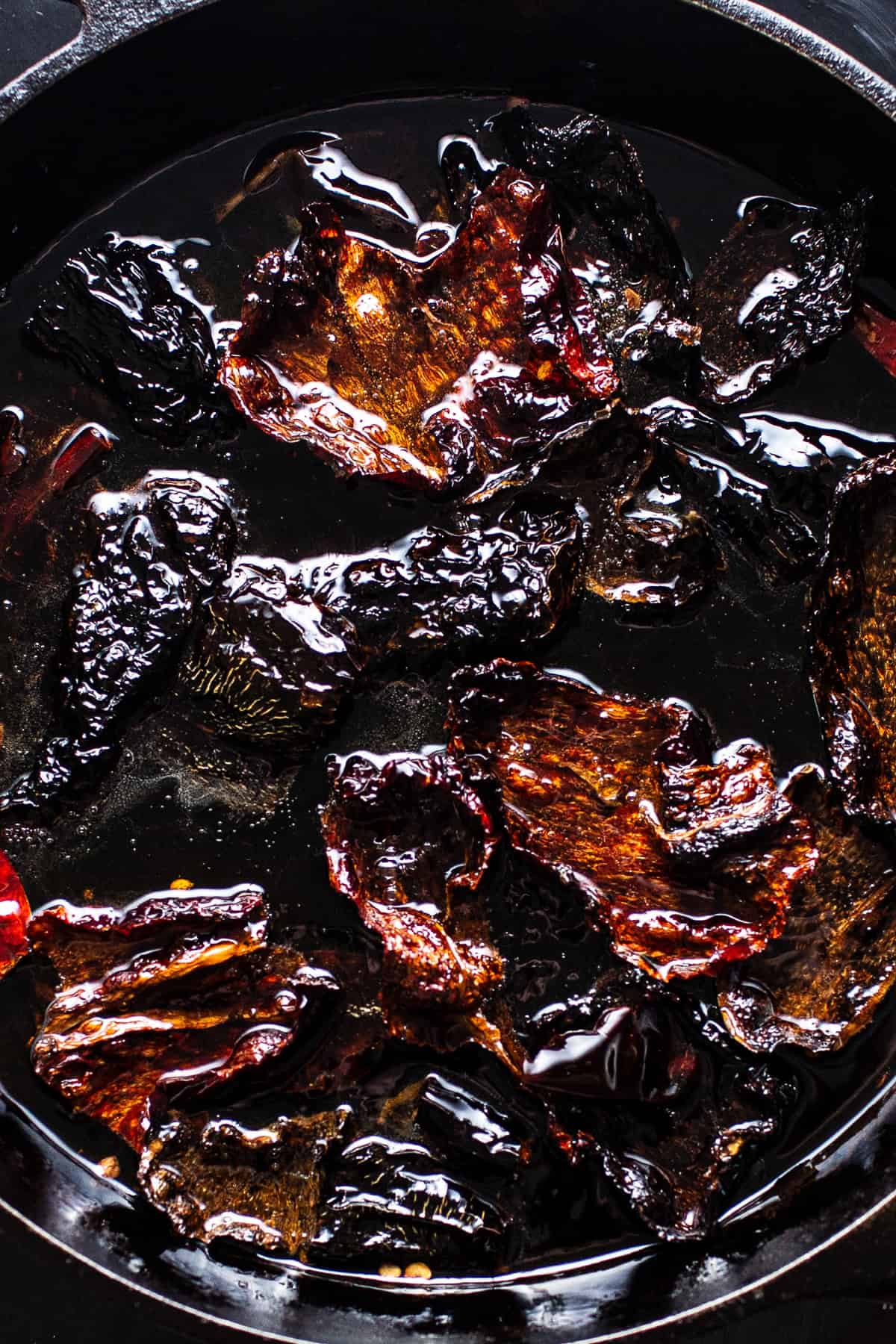 Guajillo, ancho, and árbol chiles frying in oil