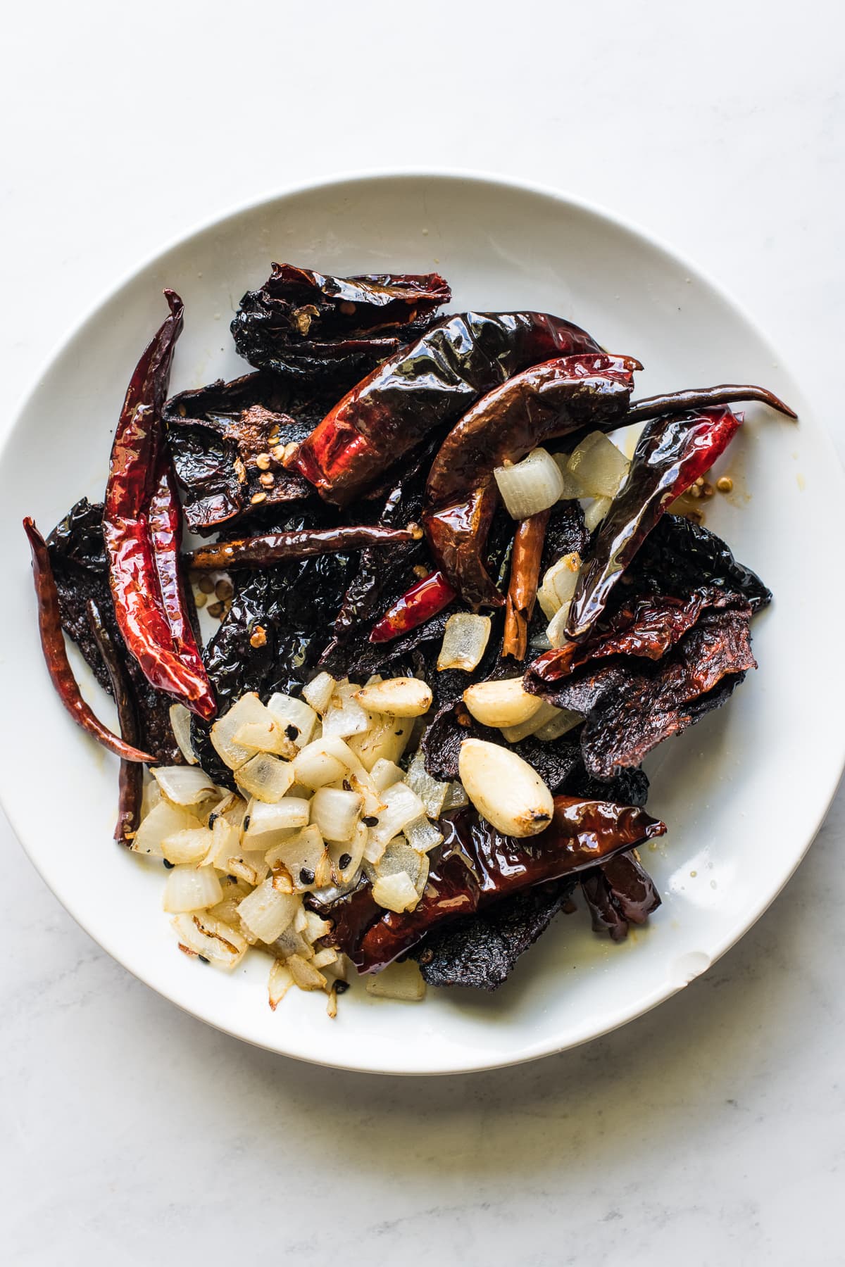 A plate full of sauteed chiles, onions, and garlic for salsa macha.