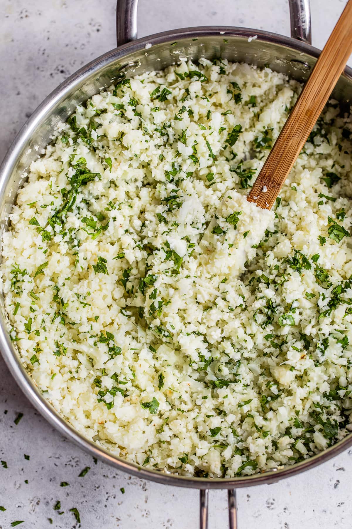 Cilantro lime cauliflower rice being stirred in a skillet.