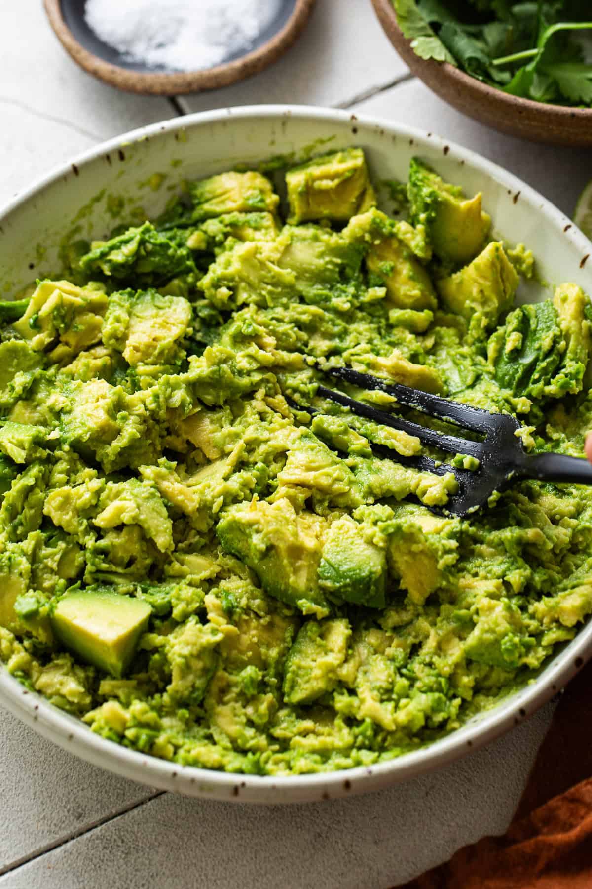Smashed avocado in a bowl with a fork.
