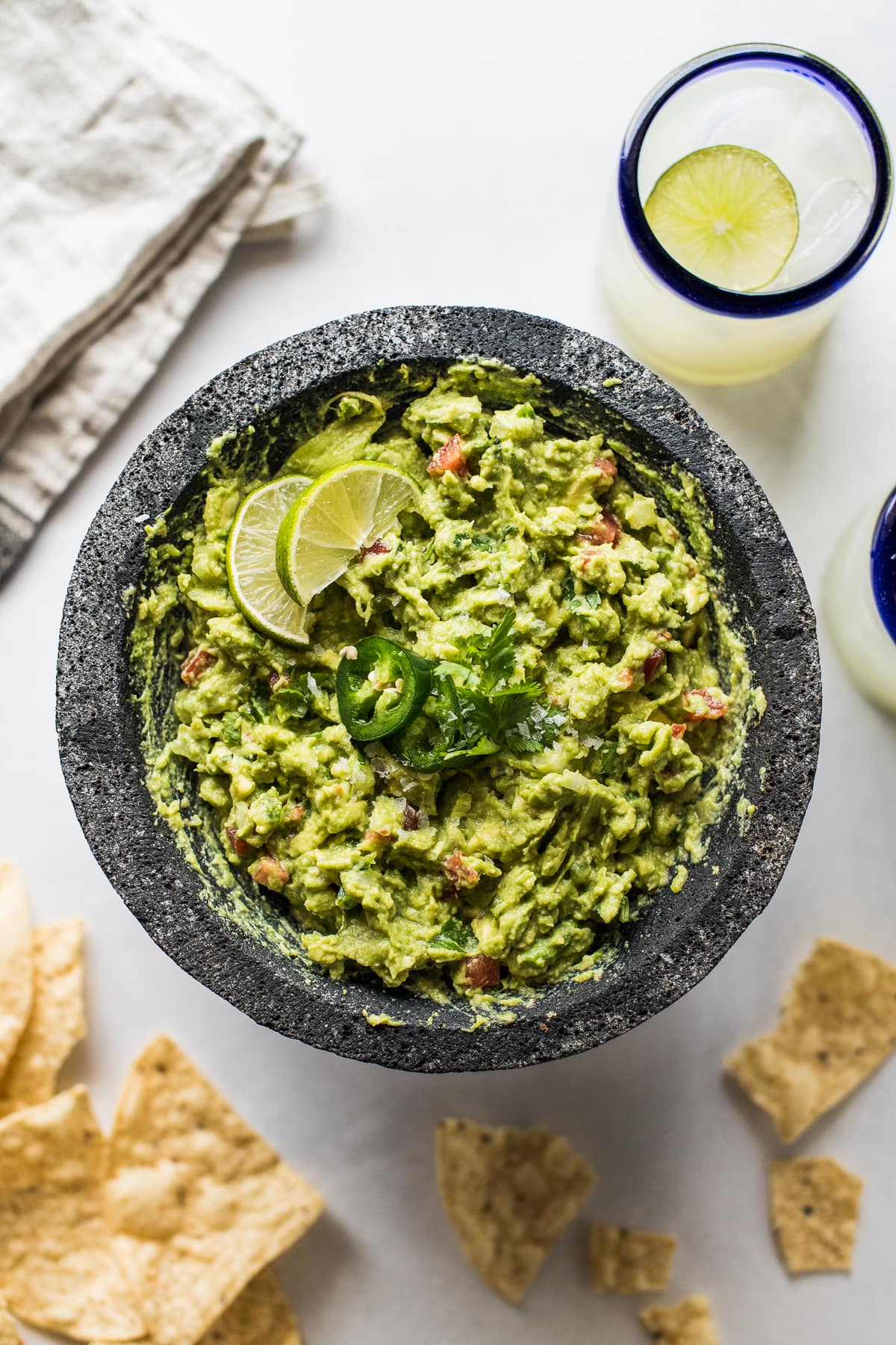 Easy guacamole surrounded by tortilla chips and a margarita.