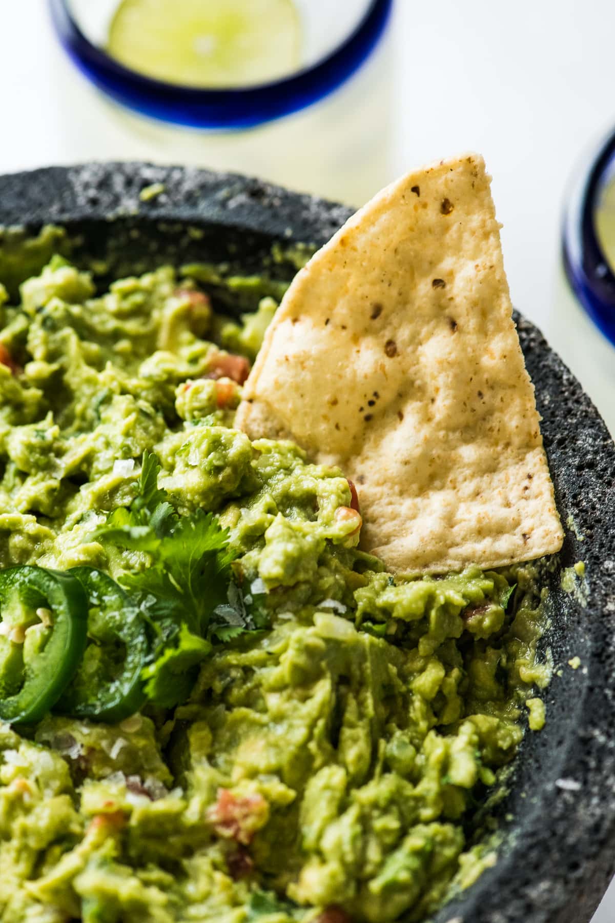 A tortilla chip being dipped in guacamole.