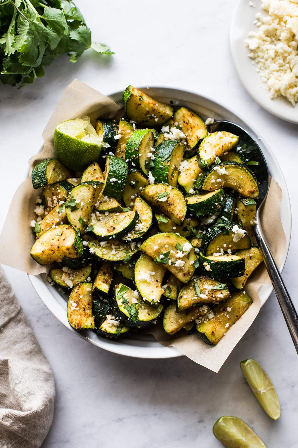 Roasted Mexican Zucchini in a bowl topped with cotija cheese, lime juice, and cilantro.