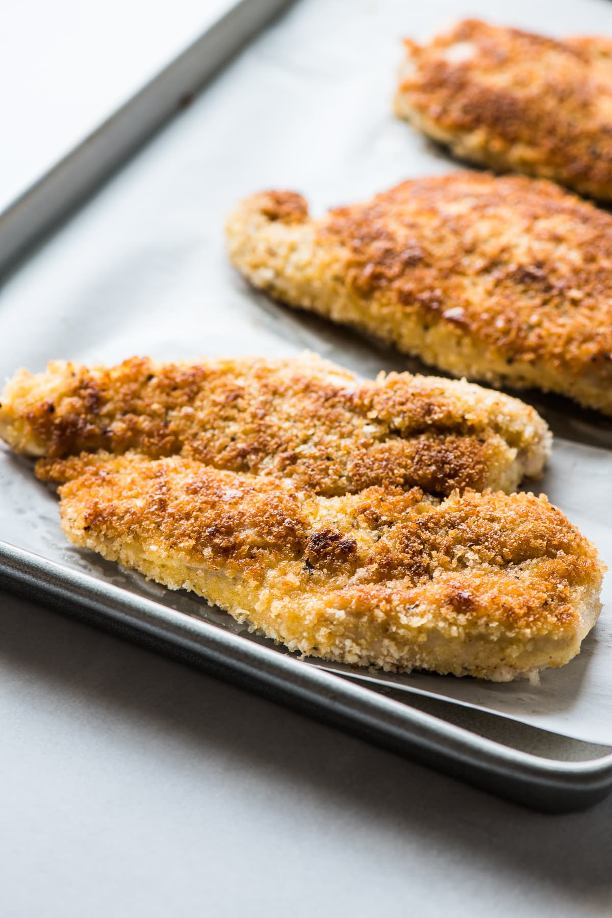 Milanesa de Pollo (Chicken Milanese) cutlets on a baking sheet.