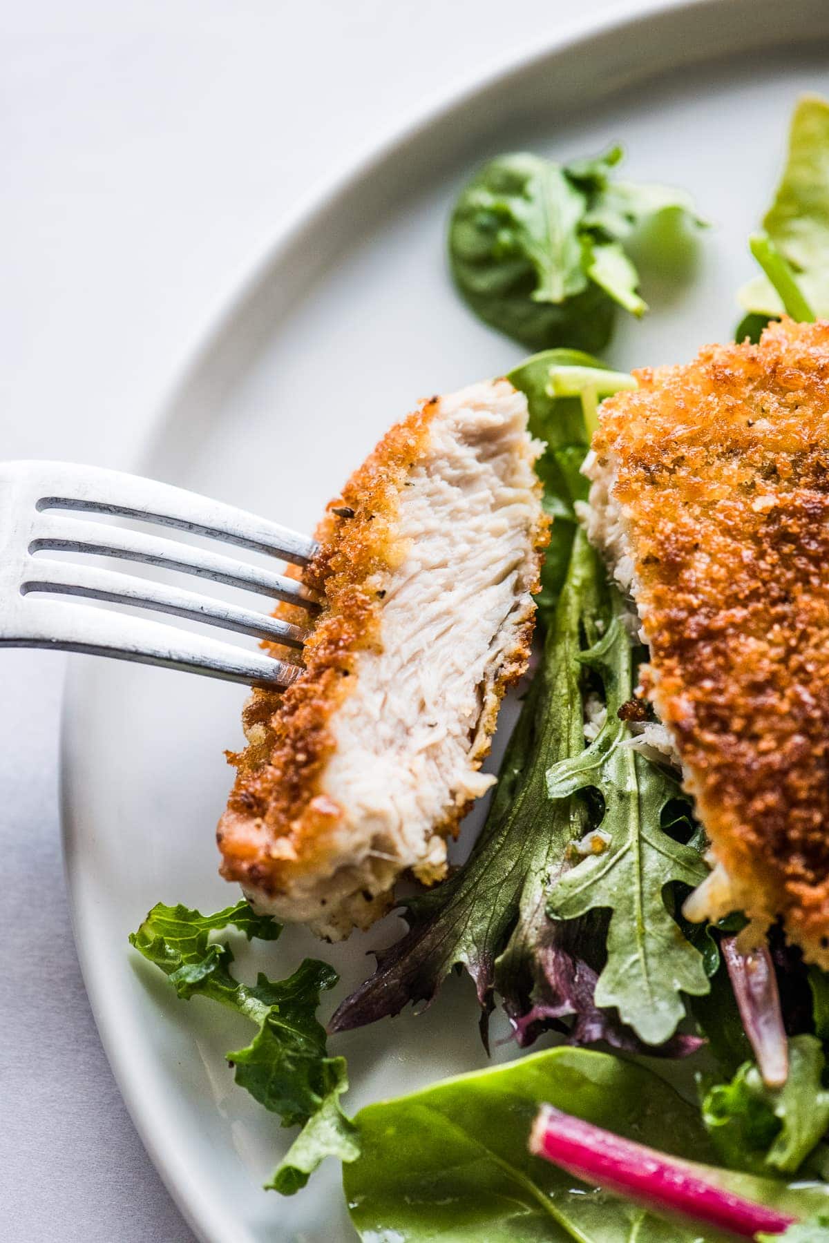 A Milanesa de pollo sliced and ready to eat on a fork.