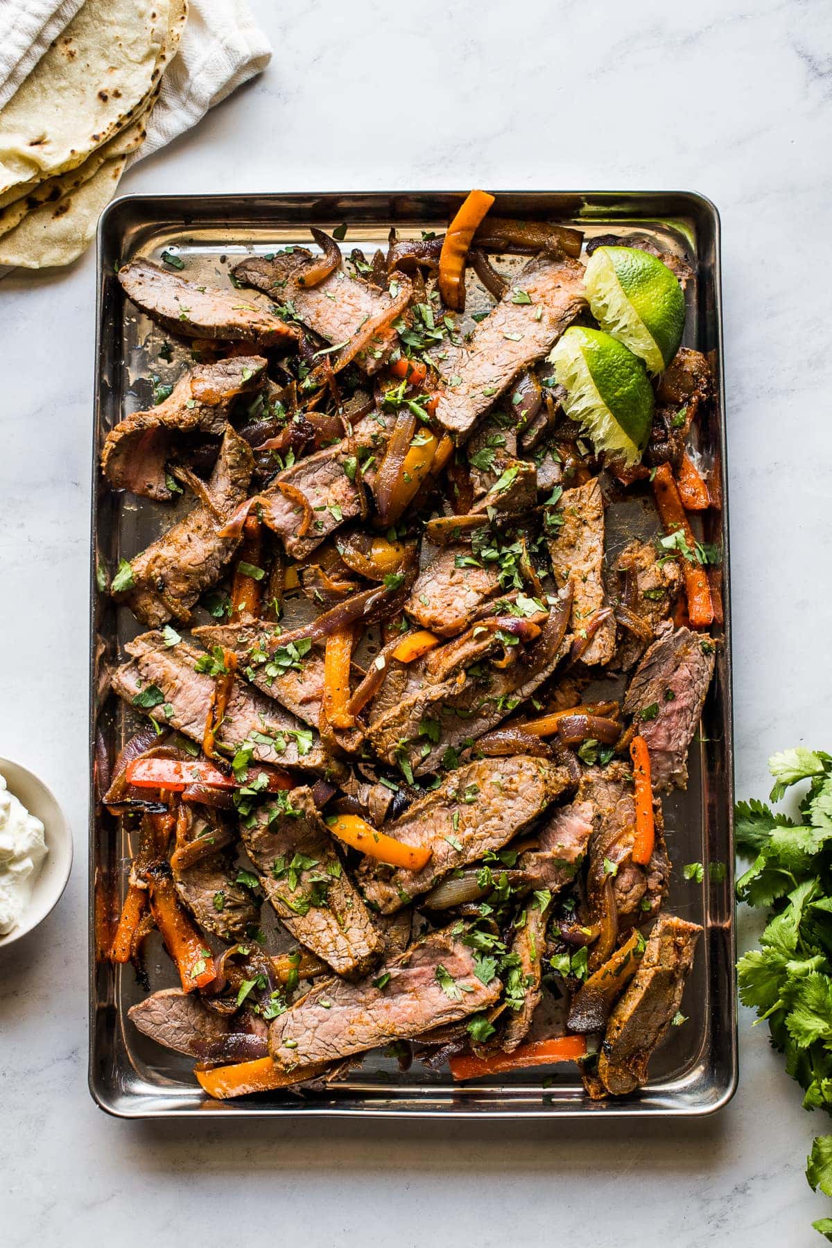 Sheet pan steak fajitas topped with cilantro.