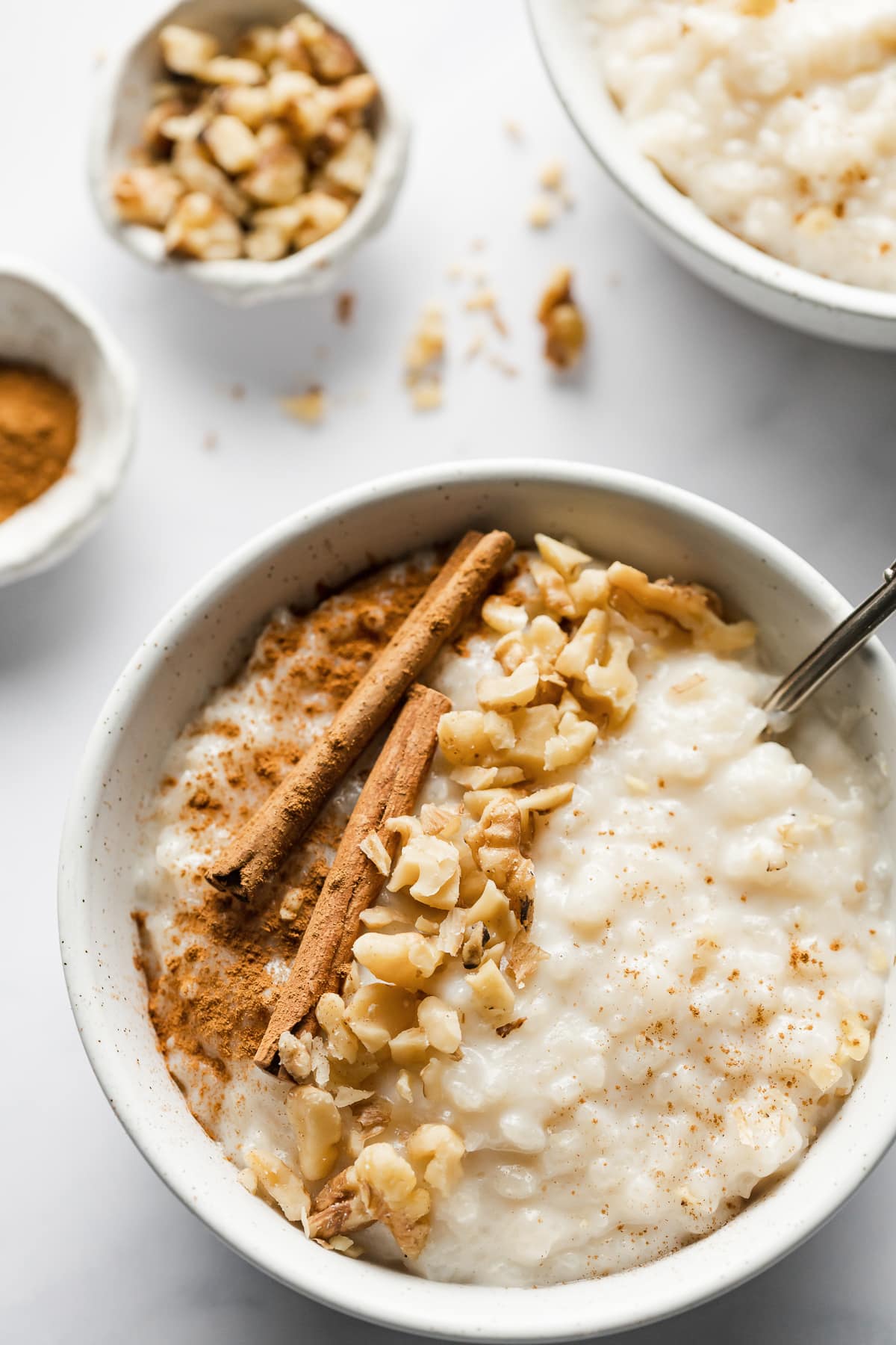 Arroz con leche in a bowl topped with chopped nuts and cinnamon.