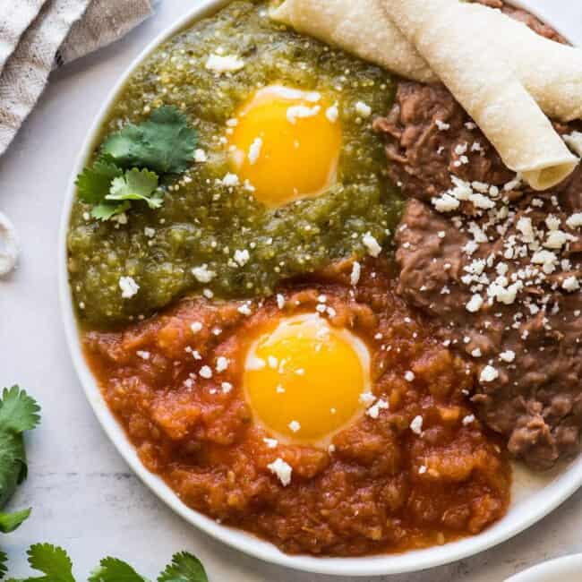 Huevos divorciados on a plate with salsa roja and salsa verde.