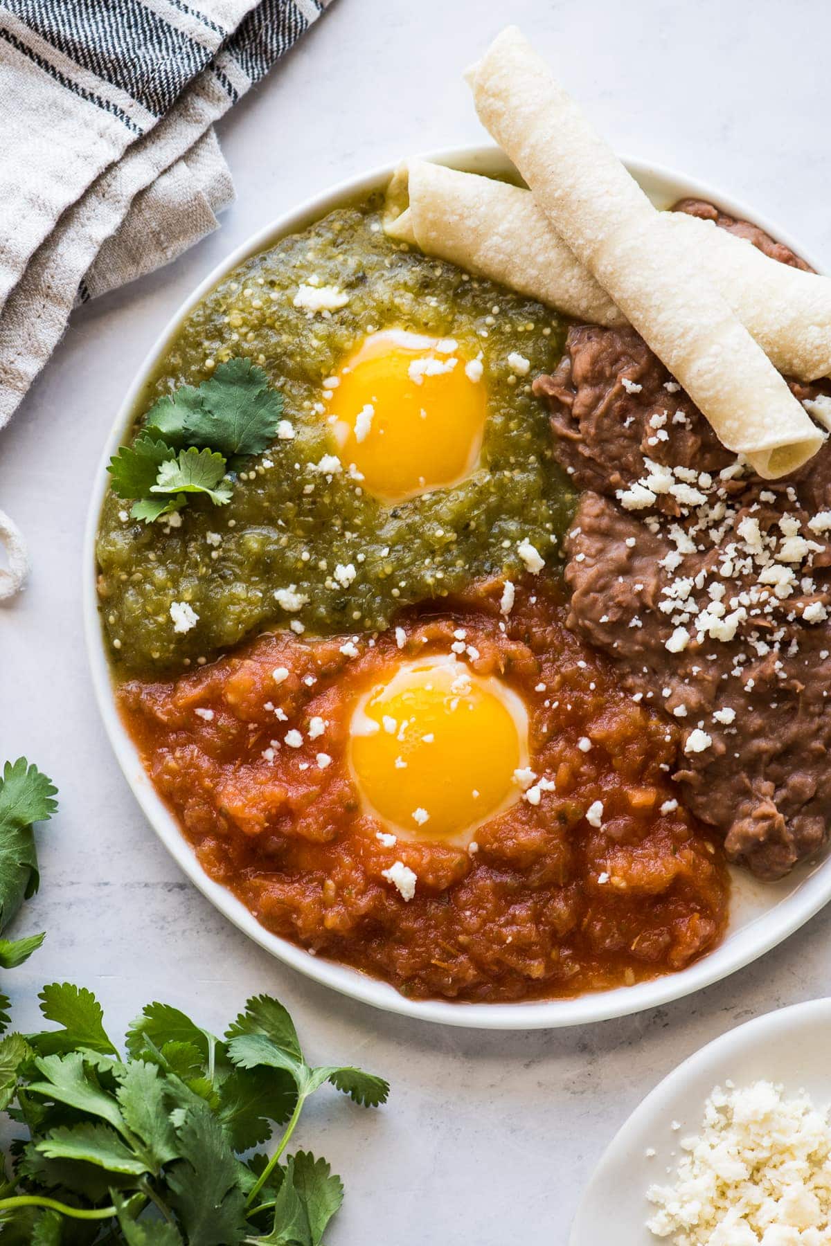 Huevos divorciados on a plate with salsa roja and salsa verde.