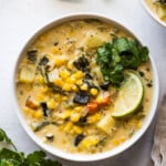 Roasted poblano corn chowder in a bowl topped with cilantro and a lime wedge.