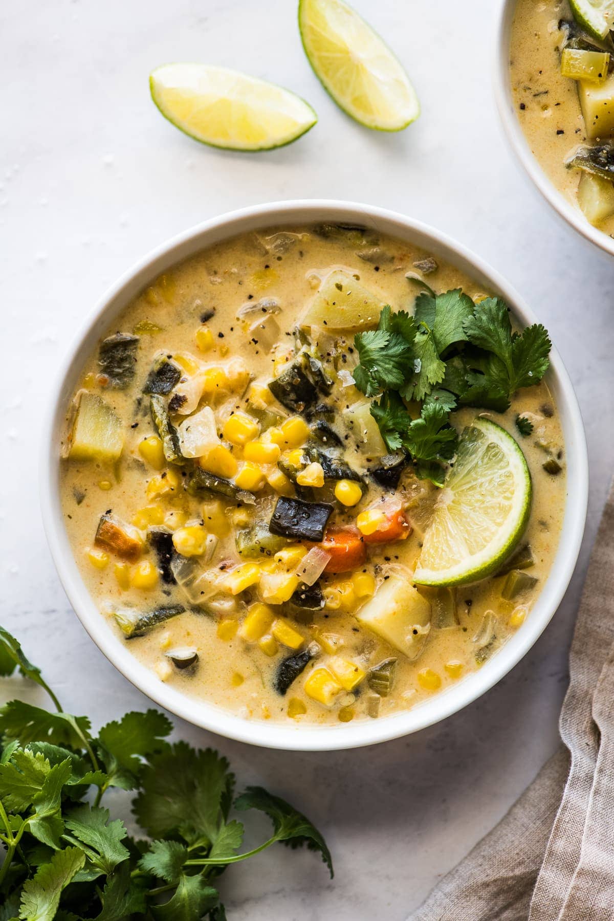 Roasted poblano corn chowder in a bowl topped with cilantro and a lime wedge.