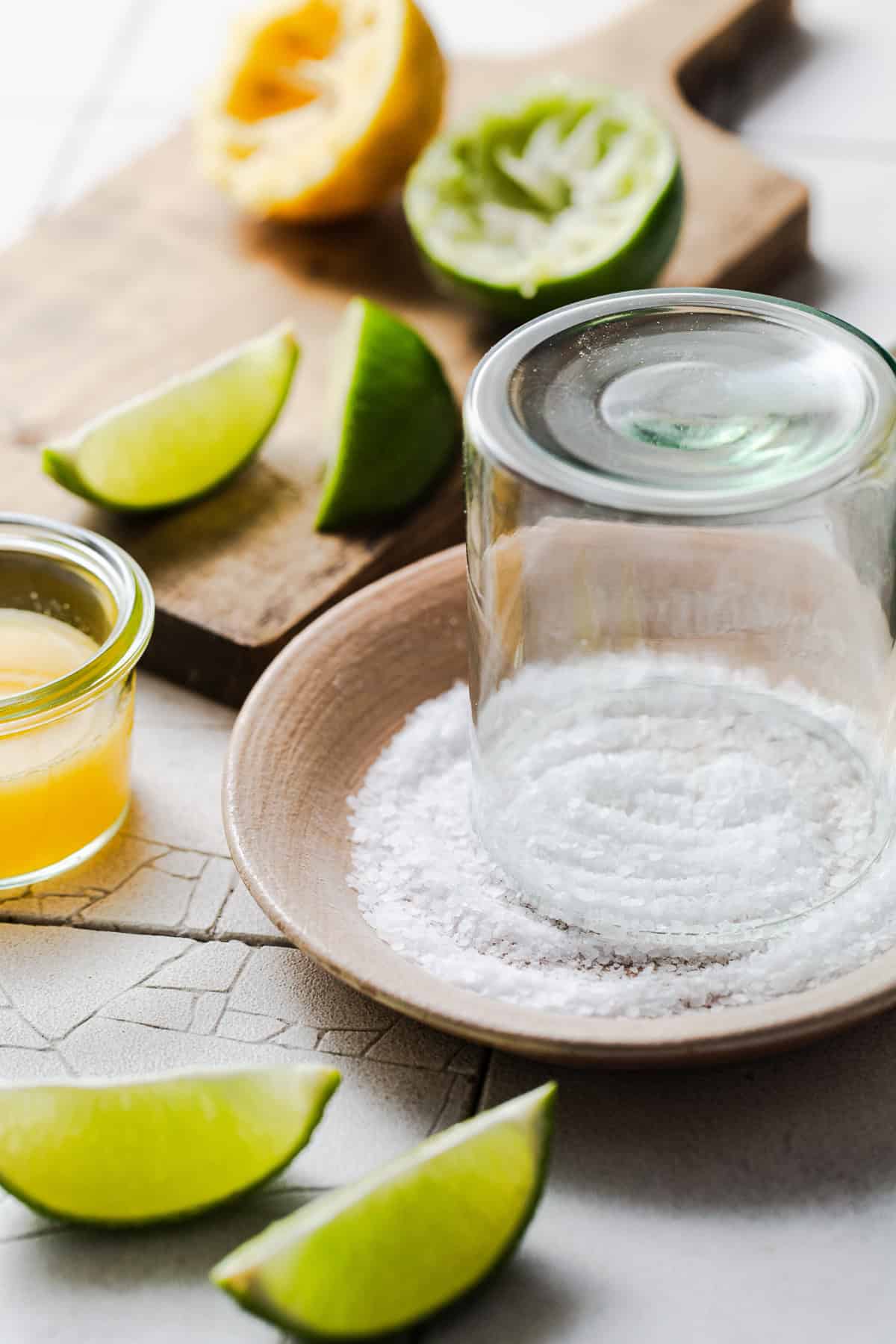 The rim of a glass being dipped in salt on a plate for a margarita mocktail.