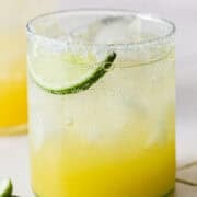 A virgin margarita mocktail in a glass with a lime wedge on a table.