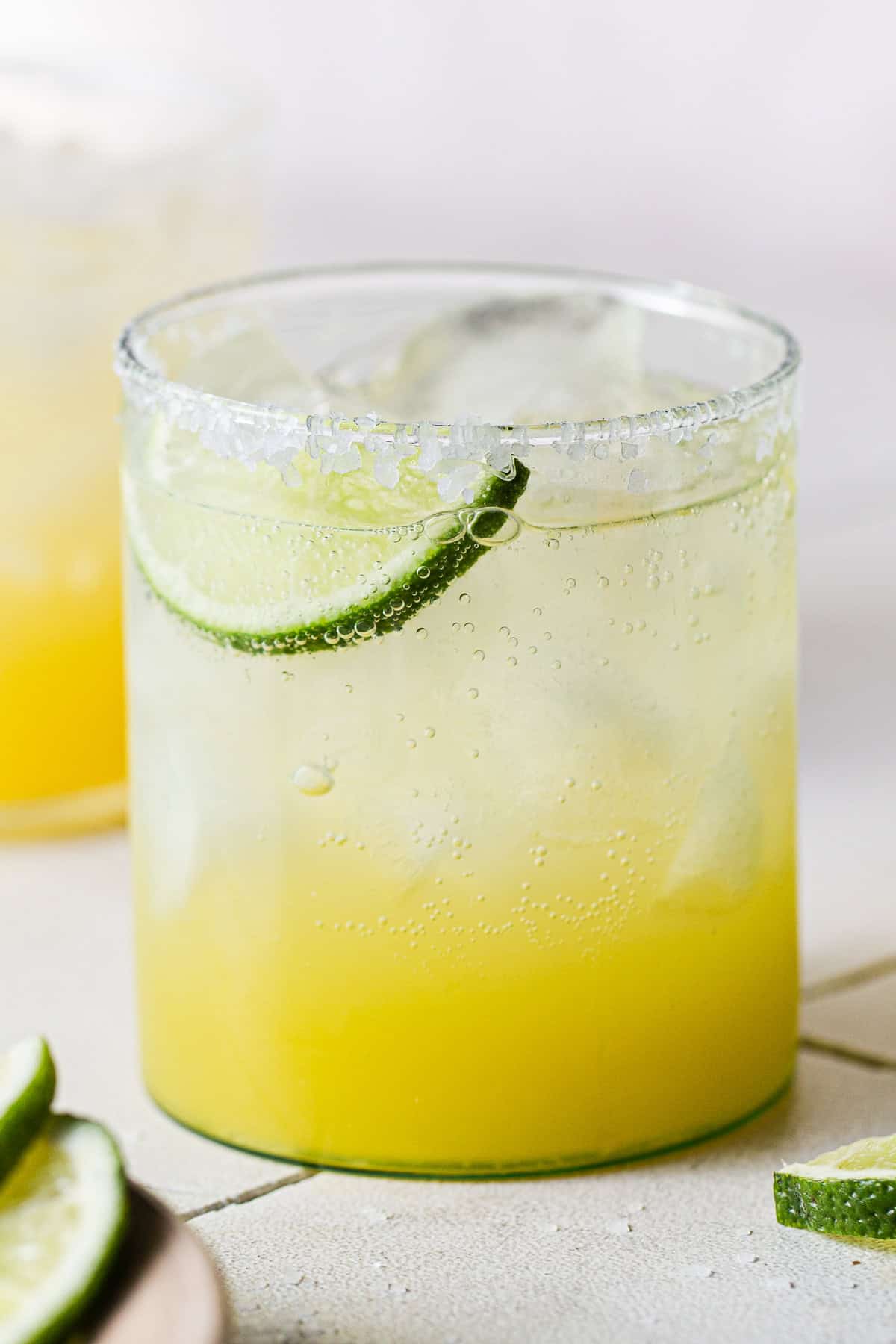 A virgin margarita mocktail in a glass with a lime wedge on a table.