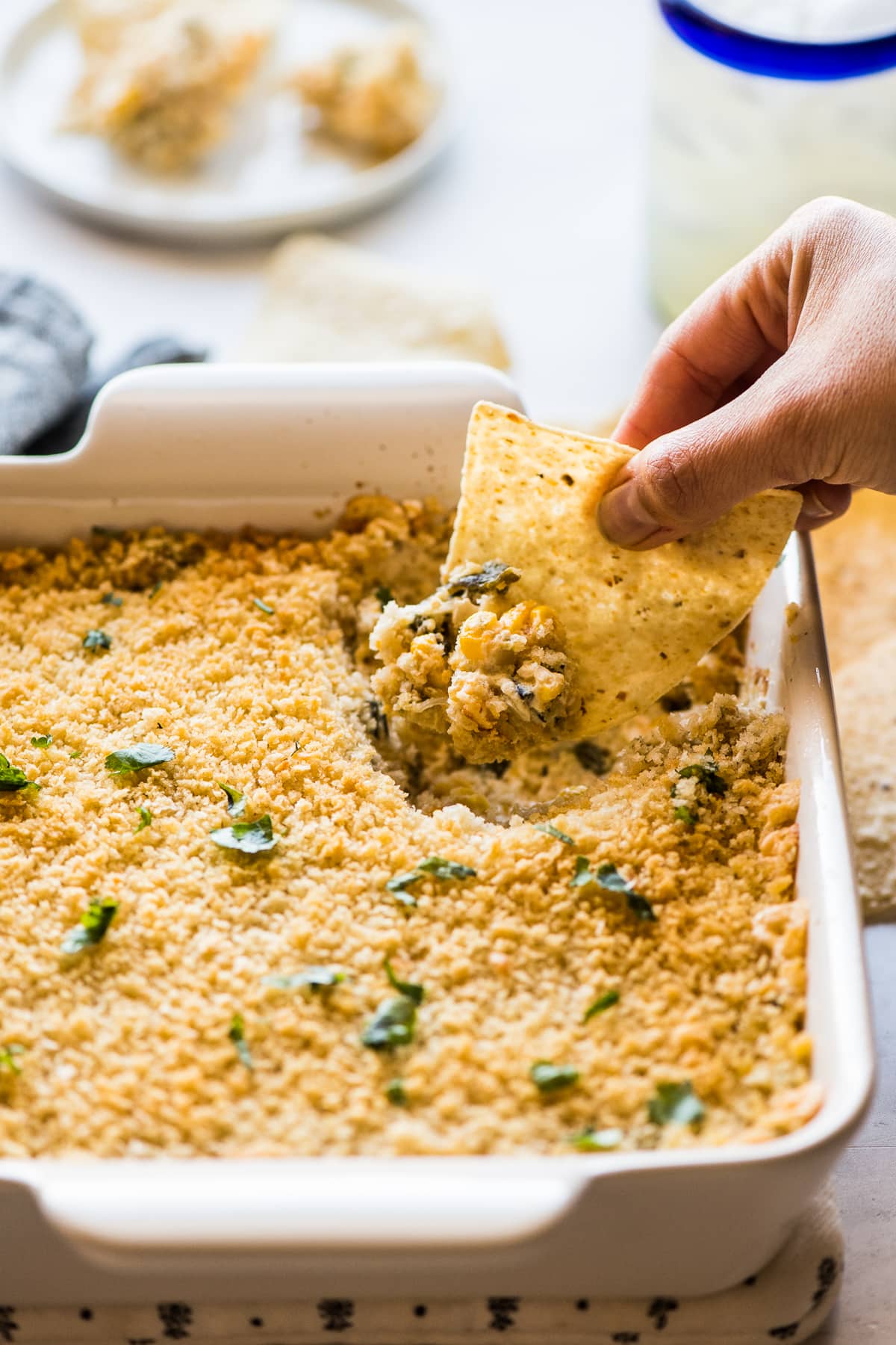 A tortilla chip being dipped into chile relleno dip.