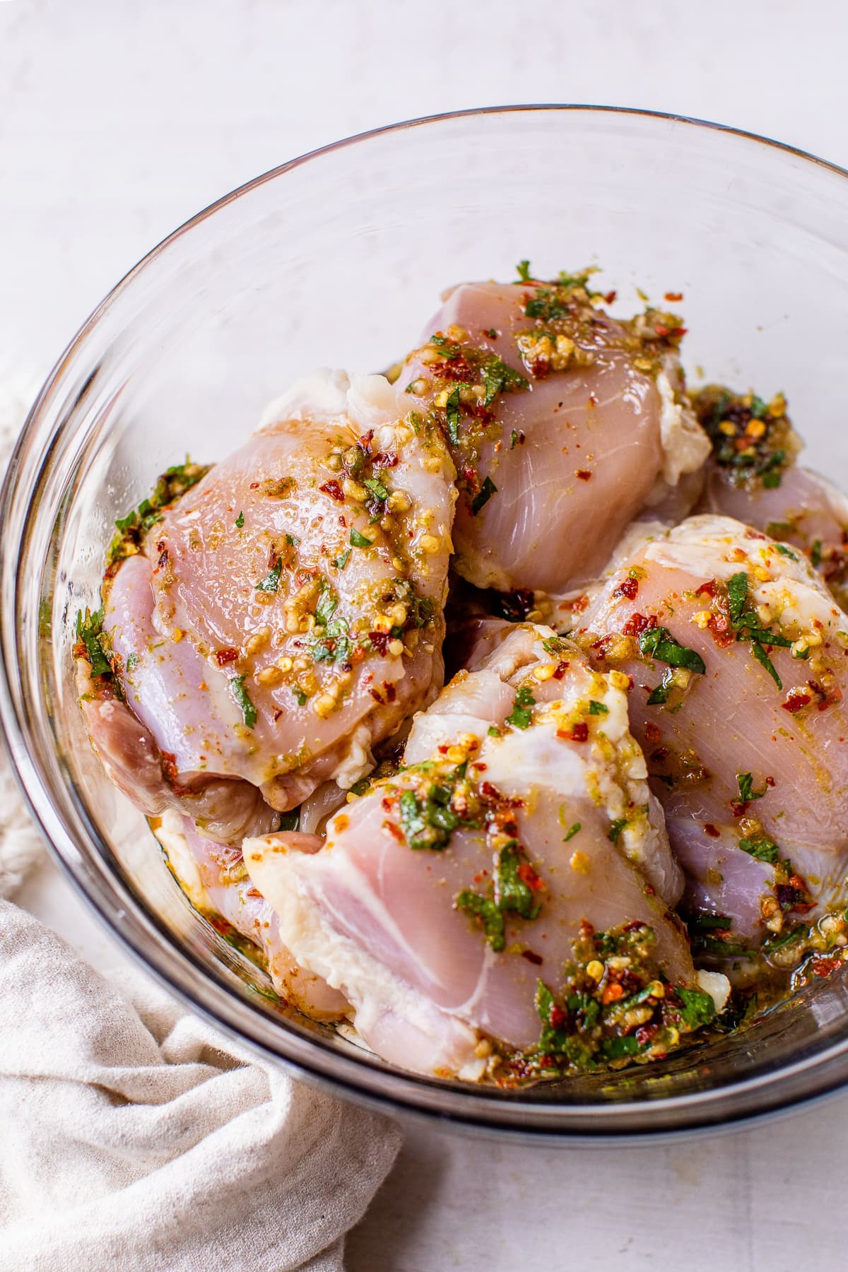 Chicken thighs being marinated in a bowl with lime chicken marinade.