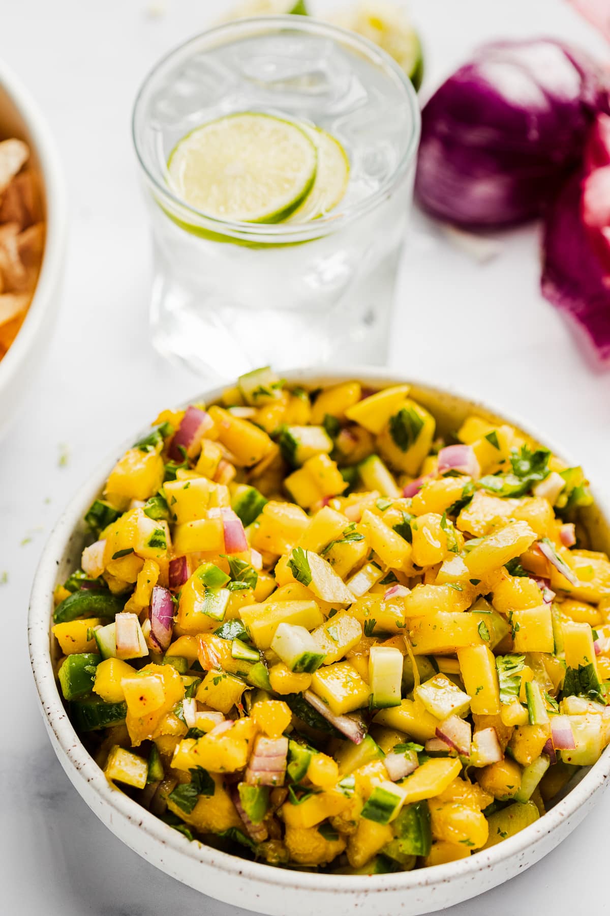 Mango salsa next to tortilla chips and an iced drink.