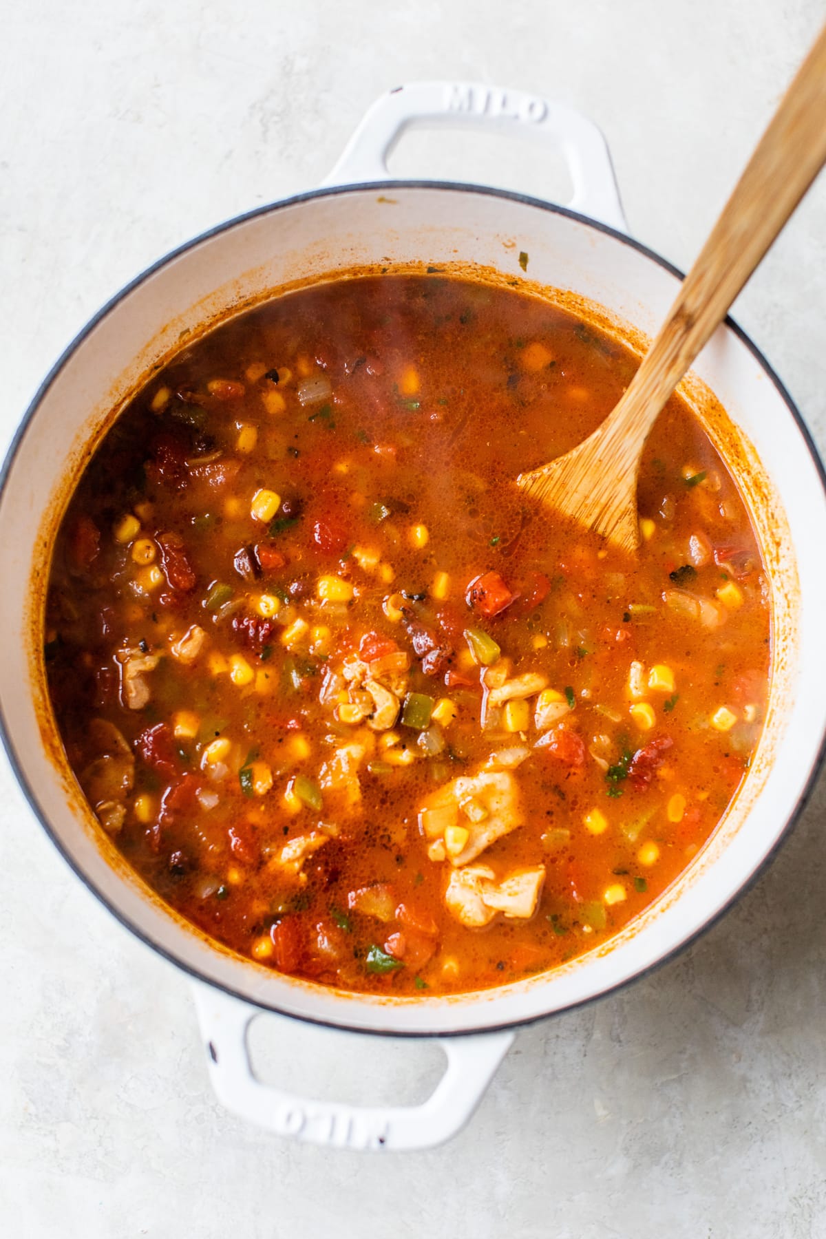 Southwest chicken soup in a pot being stirred with a wooden soup.