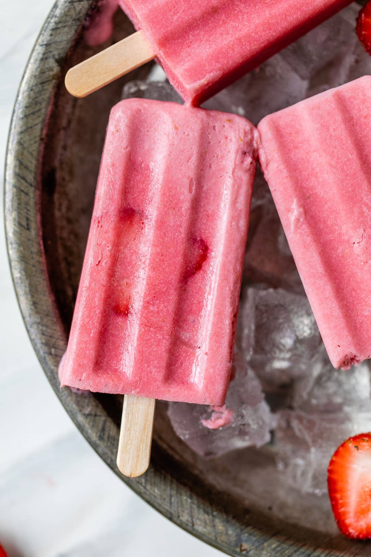 Frozen strawberry paletas on ice.