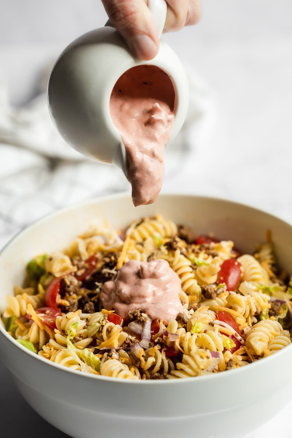 Taco pasta salad dressing being poured on dry ingredients.