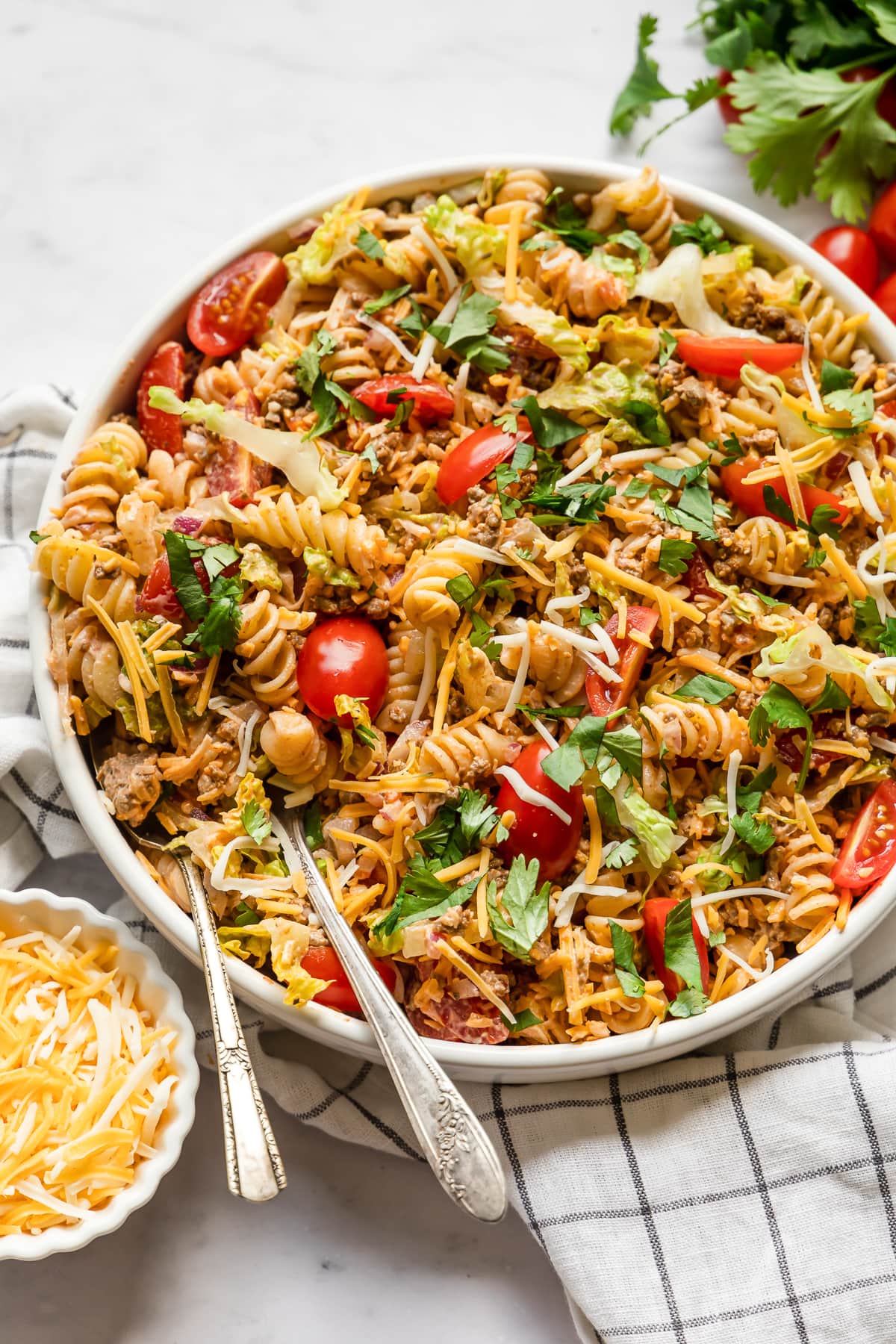 Taco pasta salad topped with shredded cheese and tomatoes.