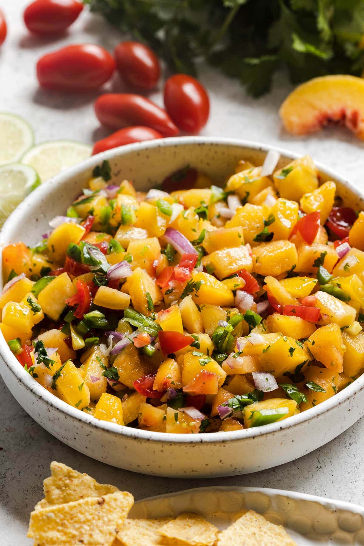 Fresh peach salsa in a bowl next to tortilla chips.