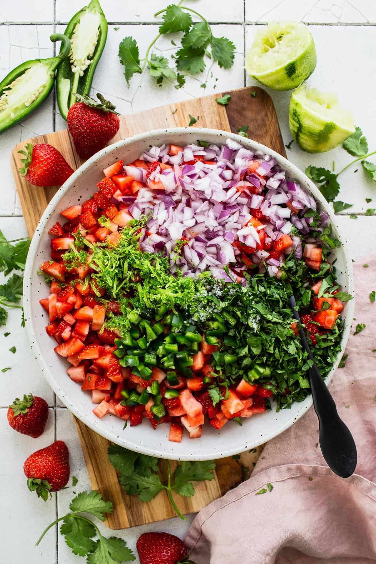 Chopped strawberries, red onion, cilantro in a bowl.