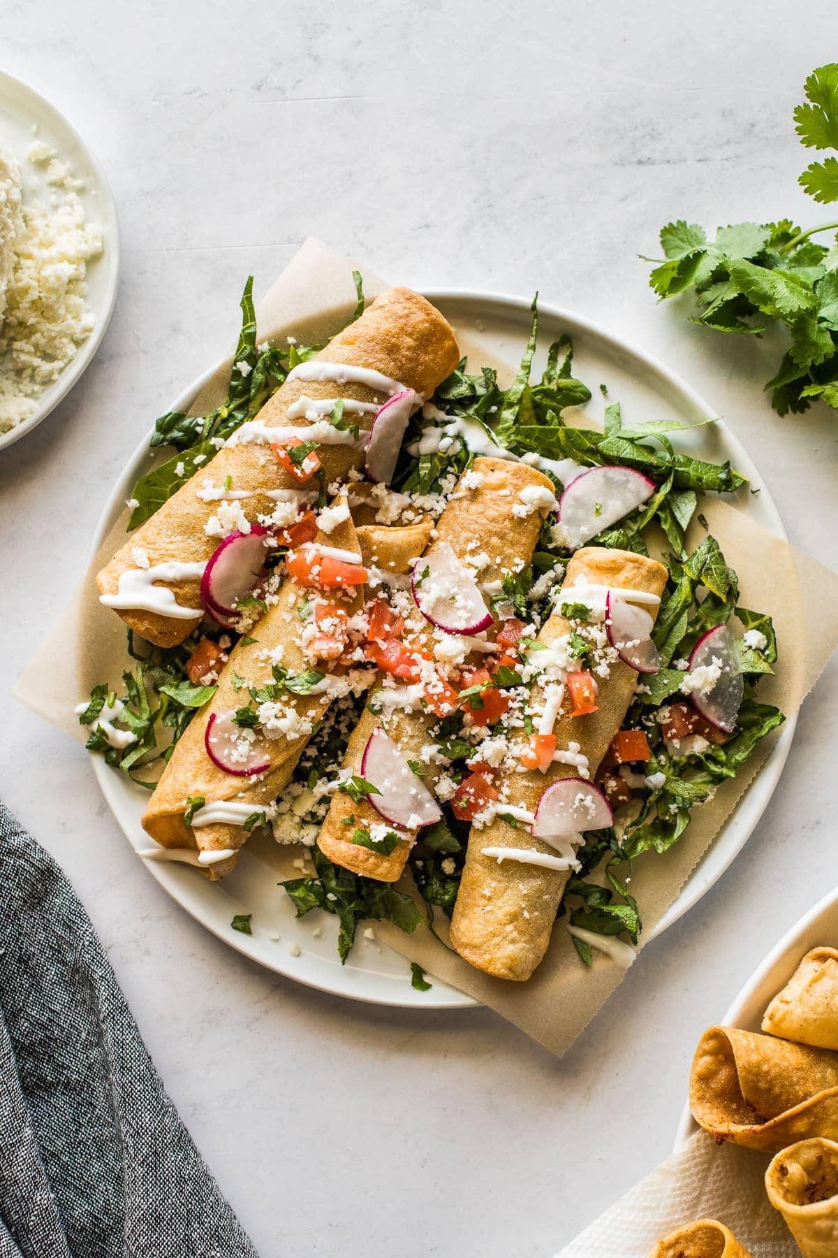 Beef taquitos topped with sour cream, avocado, and tomatoes.