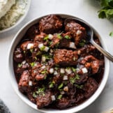 Carne adovada in a bowl next to warm tortillas.