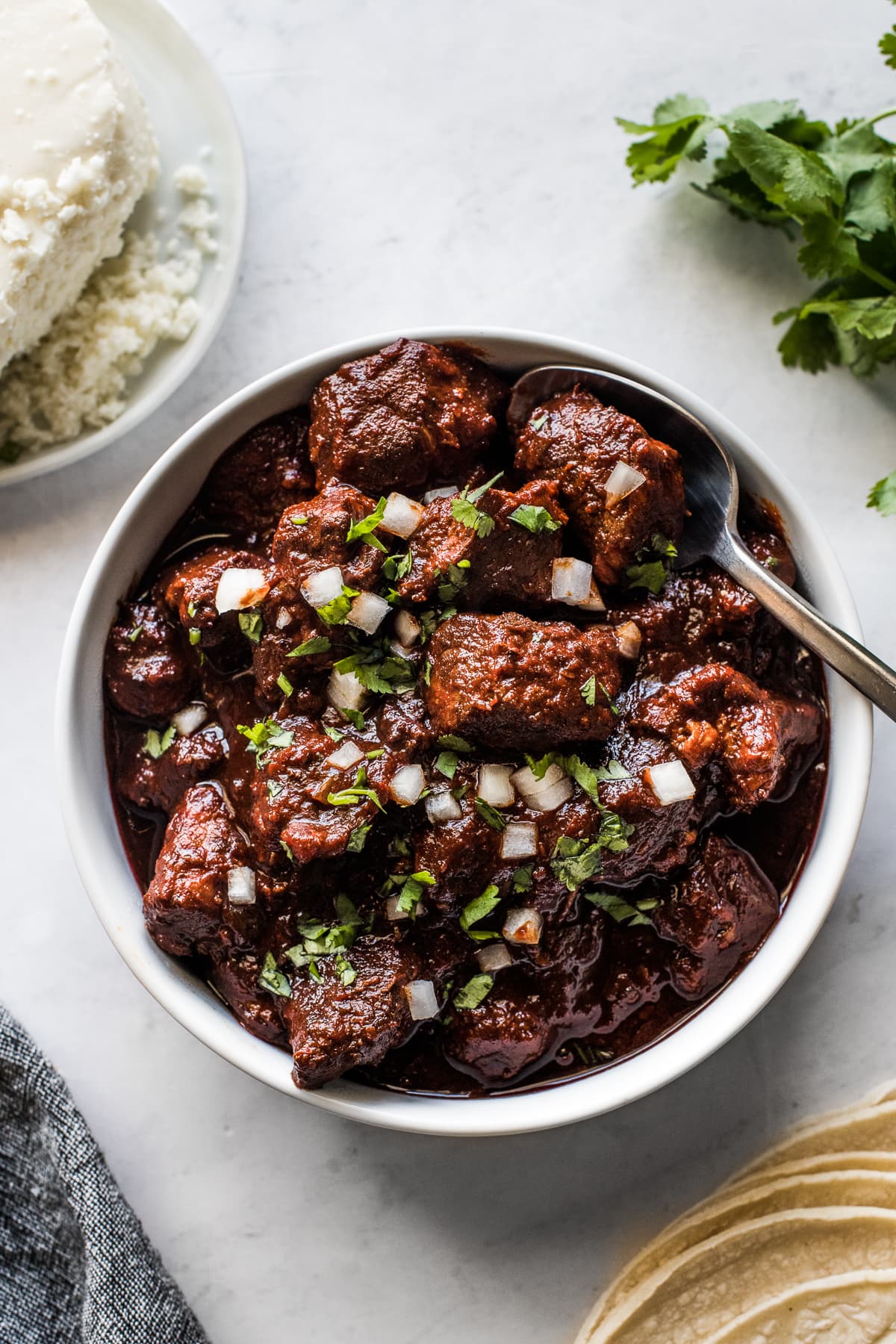 Carne adovada in a bowl next to warm tortillas.